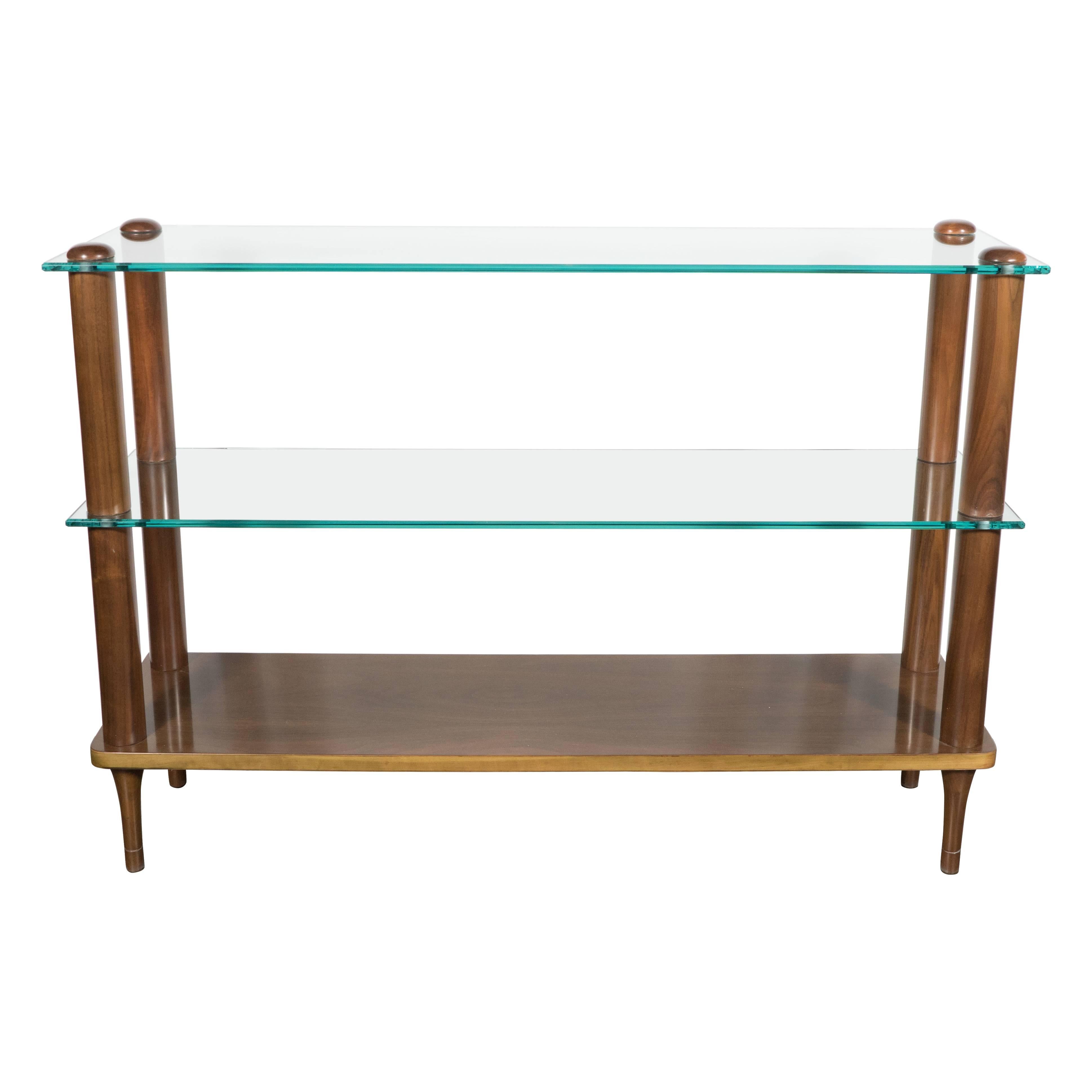 An Art Deco glass and walnut trio of shelving units by Gilbert Rohde. Each piece features three tiers: the bottom in hand-rubbed bookmatched walnut and the upper two in glass. These pieces can either be used side by side as one long unit, separately