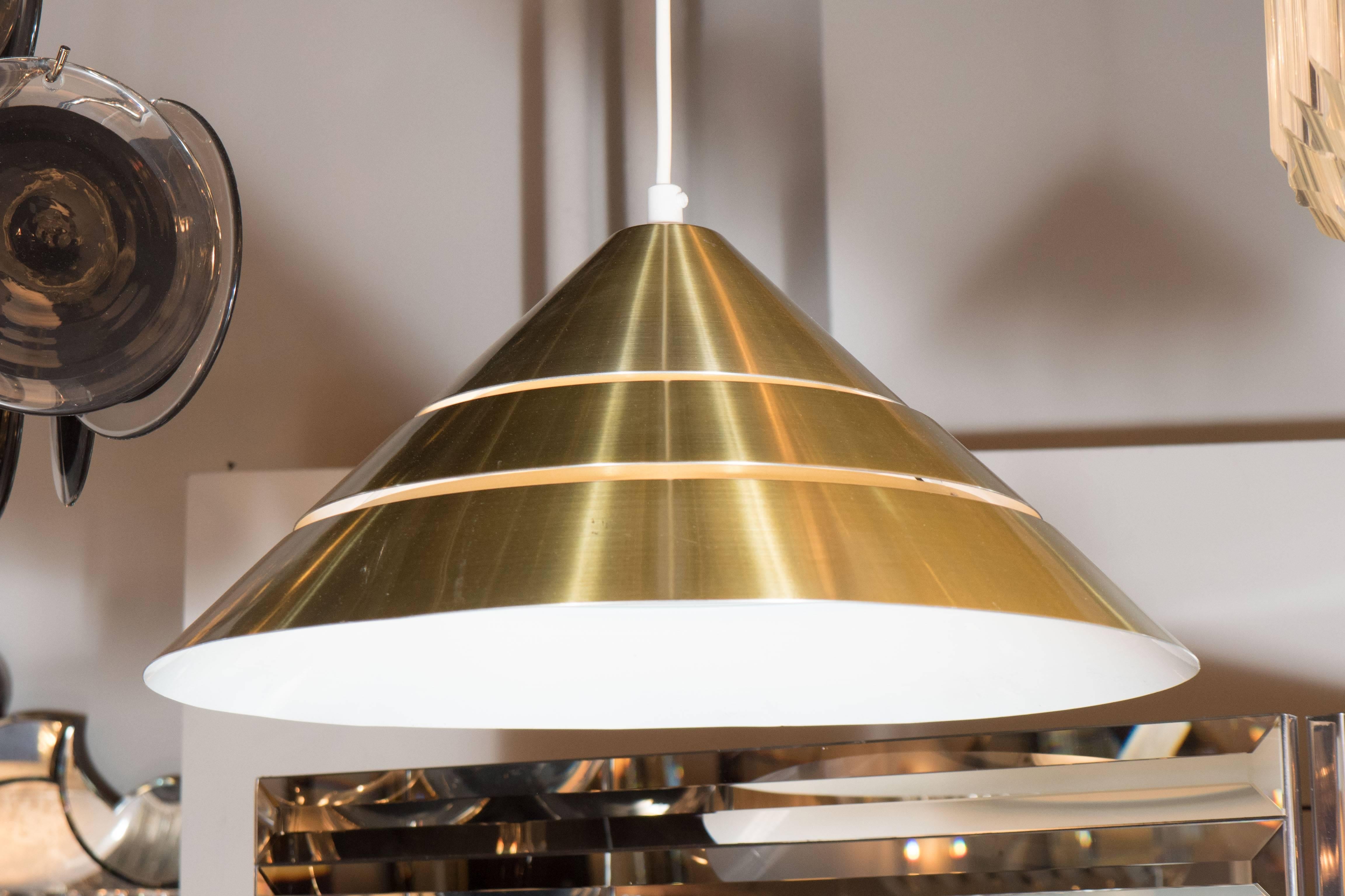 A Mid-Century Modernist segmented brass conical pendant with white enameled interior by Hans-Agne Jakobsson. The overall height on this piece can be adjusted to suit. It has been completely rewired and is in excellent condition.
