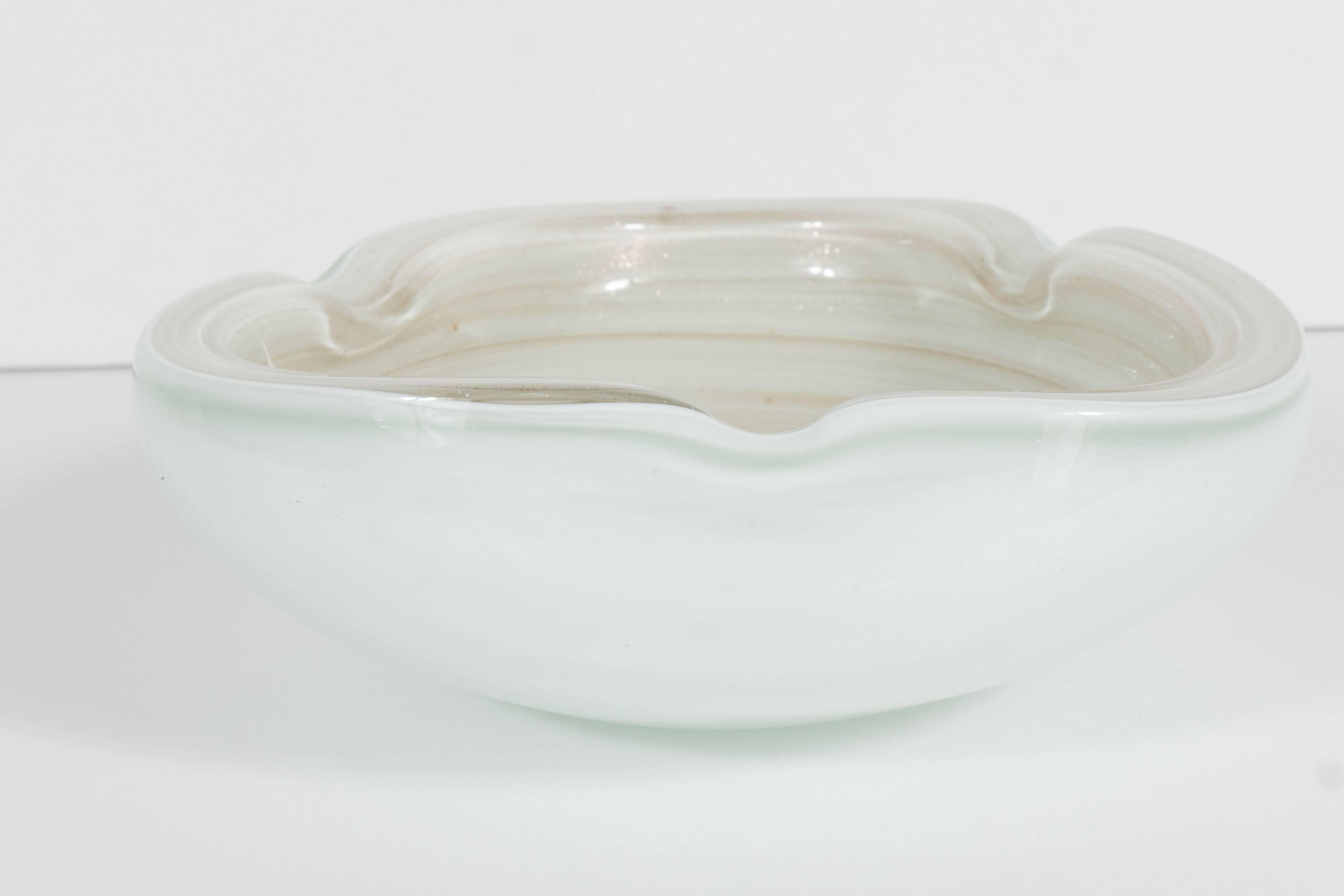 A three-sided handblown Murano glass ashtray in swirling hues of ivory and cream. This stunning piece has swirls of 24-karat rose gold throughout. This piece is in excellent condition.