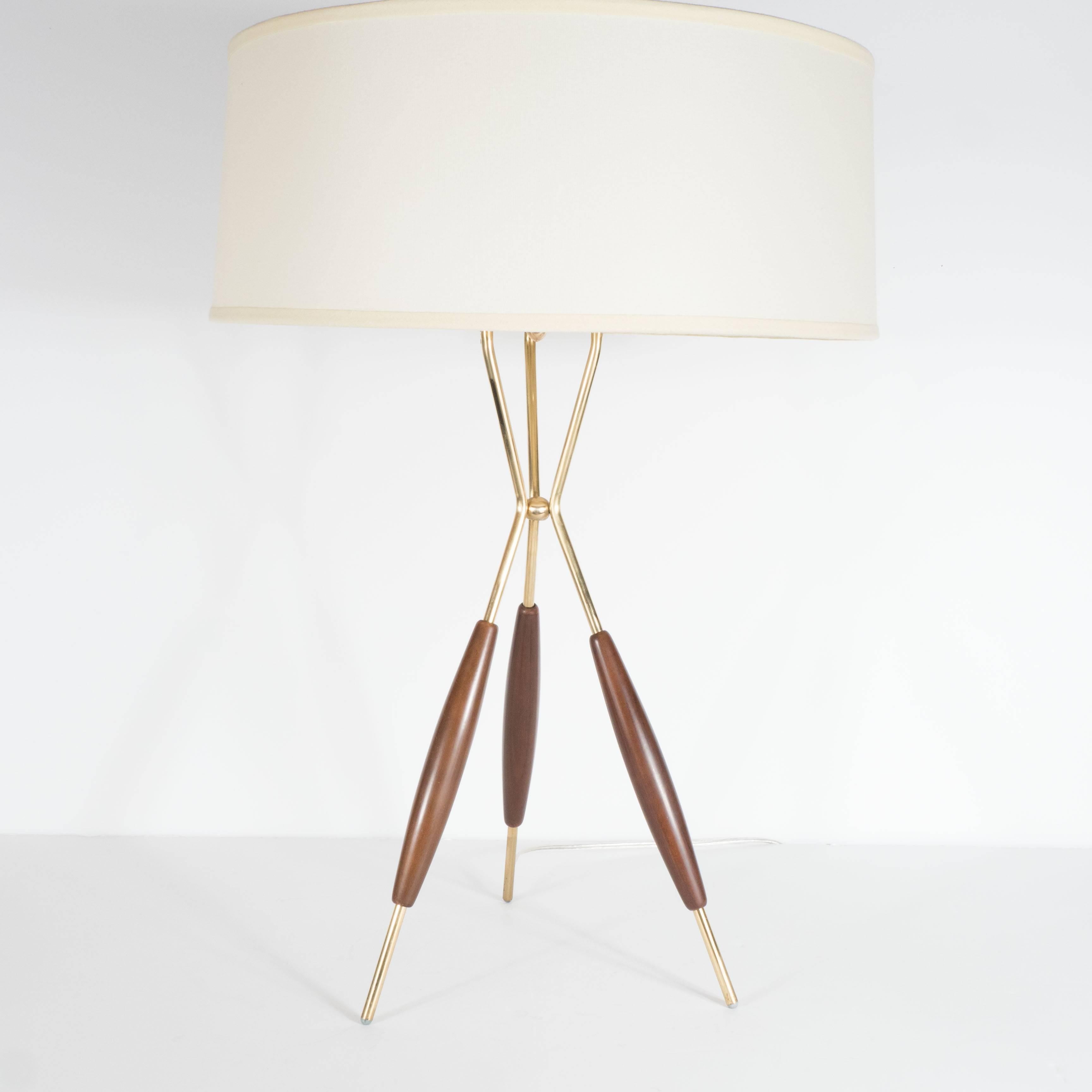 A pair of Mid-Century tripod table lamps by Gerald Thurston for Lightolier. Three rounded, polished brass rods meet at a central joining point and stem back out to support a custom fitted shade. Hand-rubbed walnut covers adorn each rod. A diffuser