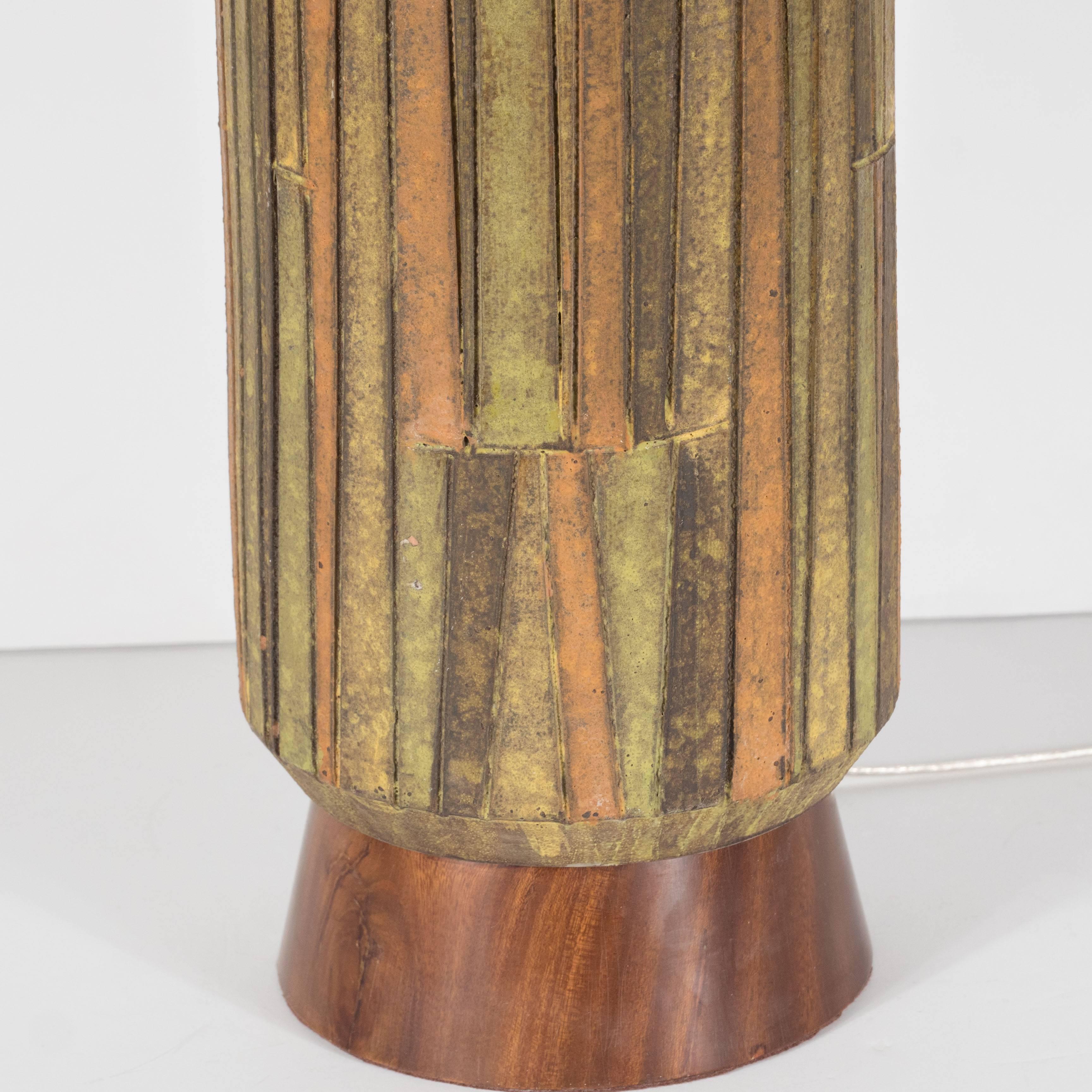 This Mid-Century Modernist earth-toned ceramic and walnut table lamp was designed by Aldo Londi and handmade in Italy by the esteemed maker Bitossi for Raymond, circa 1960. A subtly conical hand-rubbed walnut base supports a ceramic body composed a