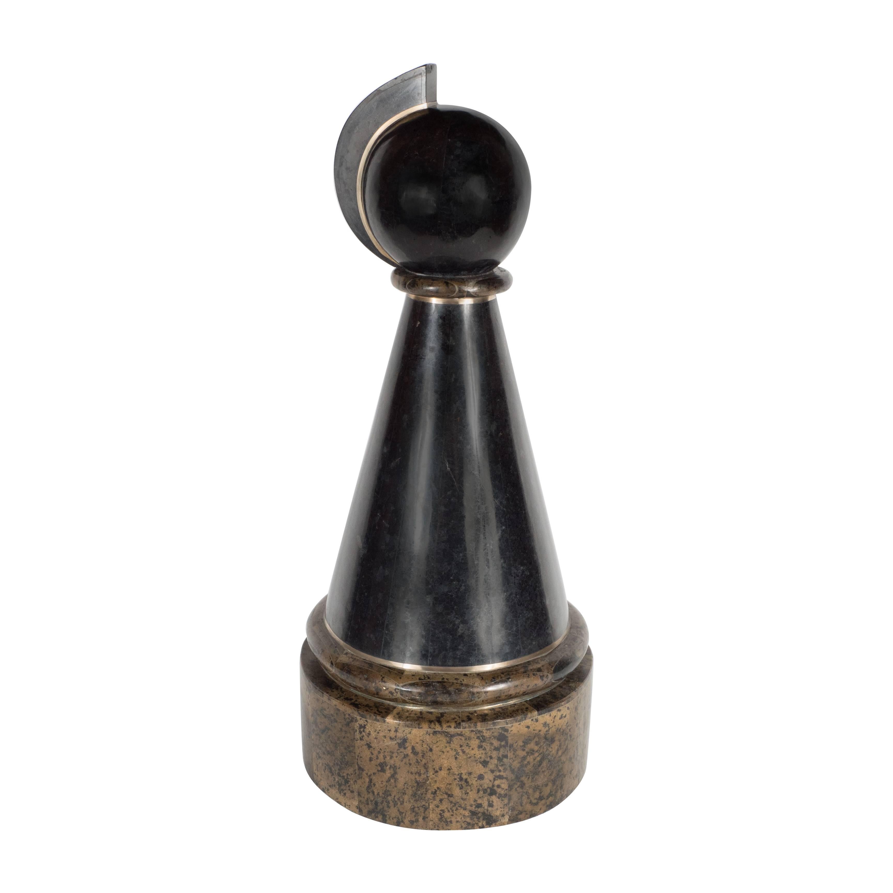 A Mid-Century modern chess piece by Maitland-Smith in various types of tessellated stone. Bands of brass inlay accentuate the piece. Vertical bands of black stone segments make up the conical body of the piece, which earth-toned shades cover the