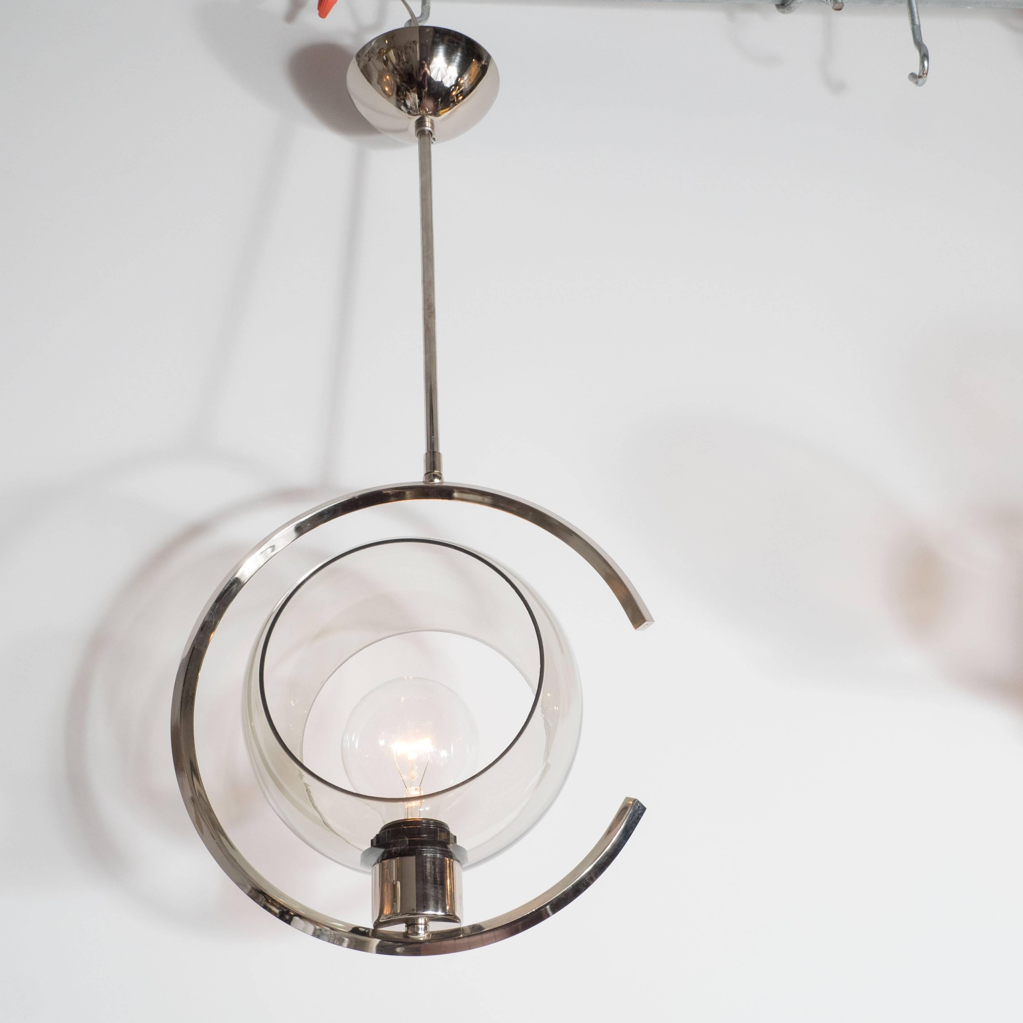 A Mid-Century Modernist concentric design chrome and glass pendant. This chandelier features a tubular chrome rod which supports a C-shape frame, in which rests a single Edison-based socket and circular curved smoked glass shade with exposed sides.