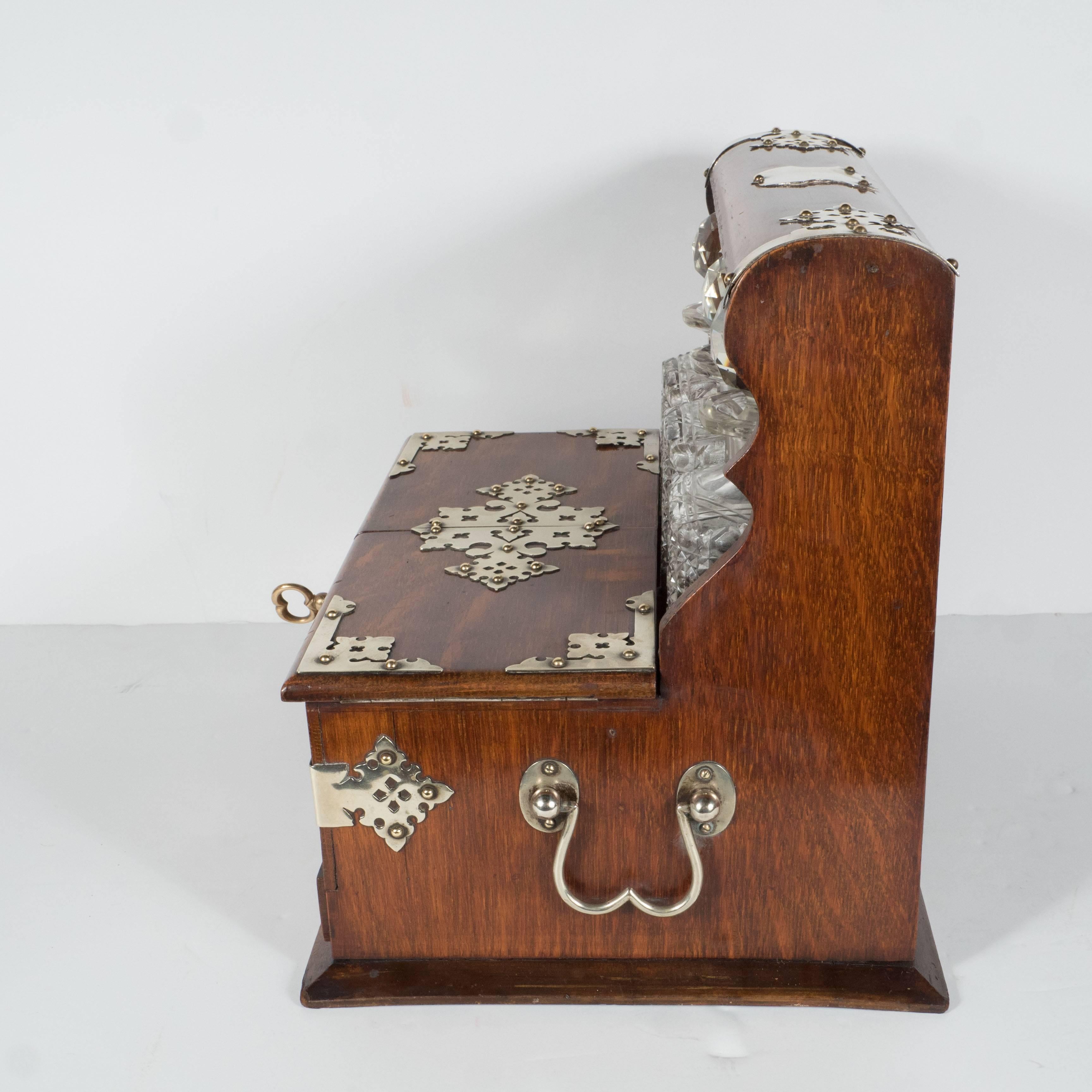 Victorian silver plate Mounted golden oak and cut-glass Tantalus/Decanter box,
Late 19th century.
It also features a hidden drawer with a secret lever to open it. Wonderful silver plate hardware.
With three hobstar-cut bottles fitted into the