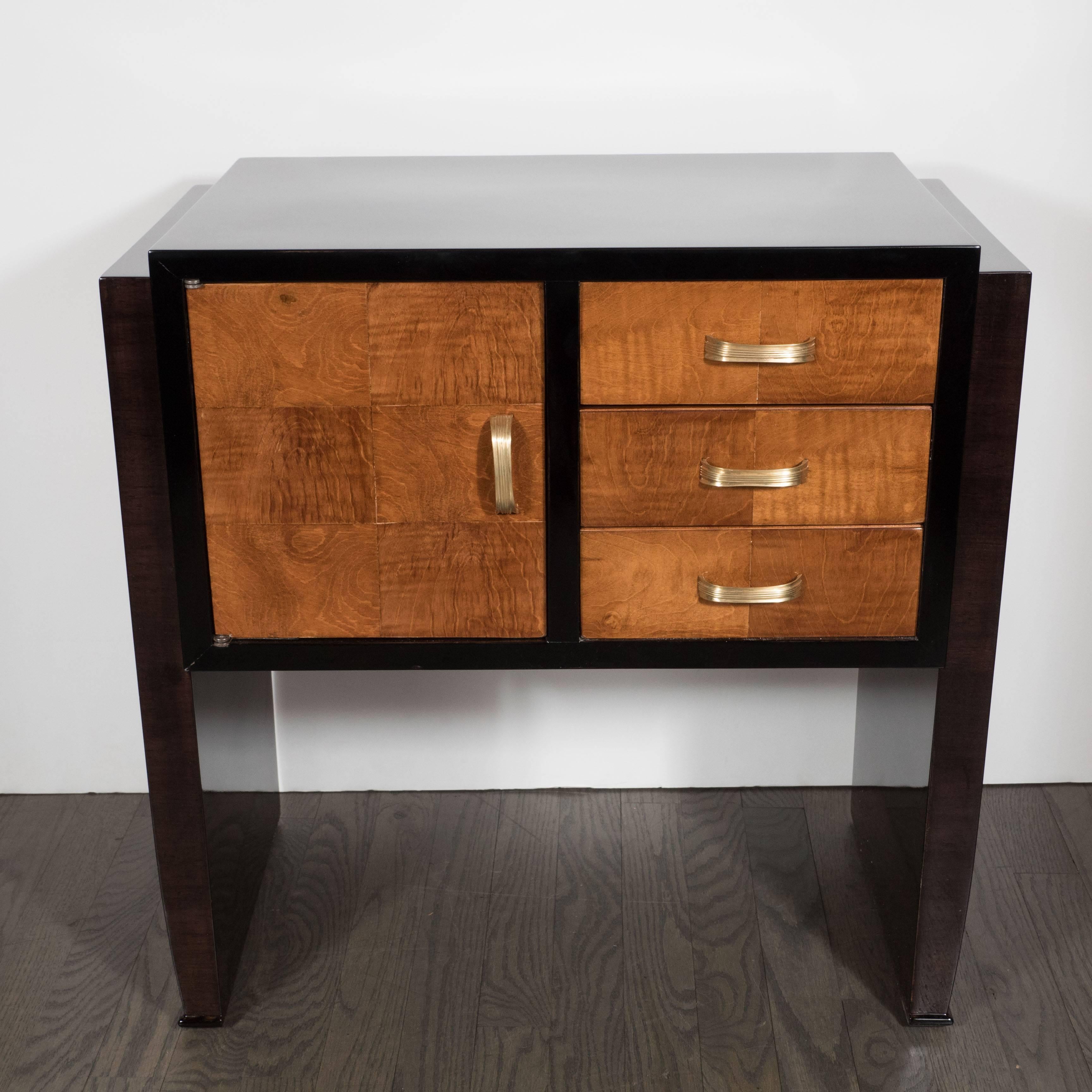 An elegant pair of Art Deco nightstands or end tables in bookmatched burled elm and ebonized walnut with streamlined brass pulls, each nightstand fitted with three drawers and one cabinet door. The drawers and cabinet doors are decorated with