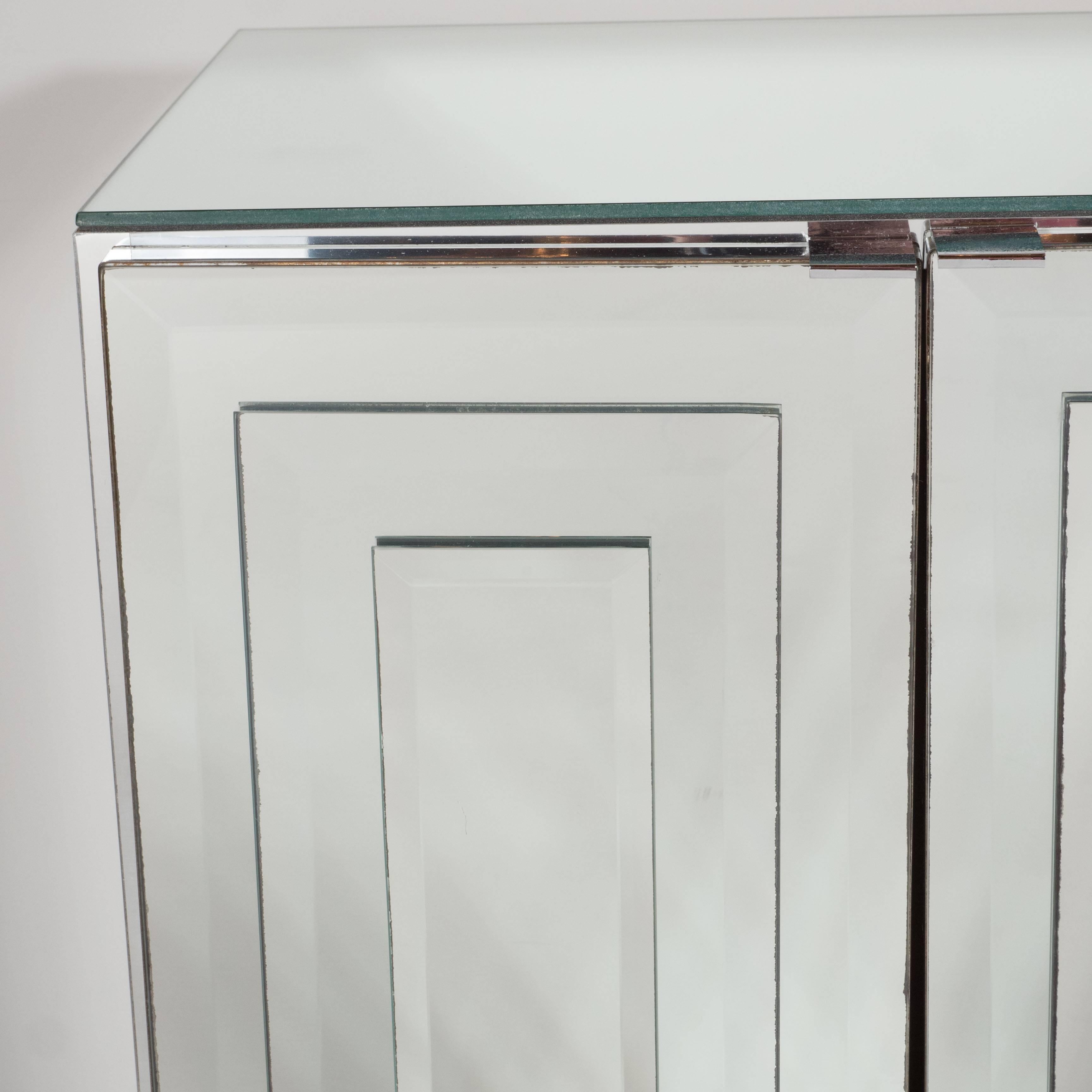 Pair of Mid-Century skyscraper style wide-bevel stacked panel mirrored nightstands or end tables in by Ello. Minimal polished chrome support handles, when pulled, reveal storage with one adjustable shelf, featuring a white lacquered interior finish.