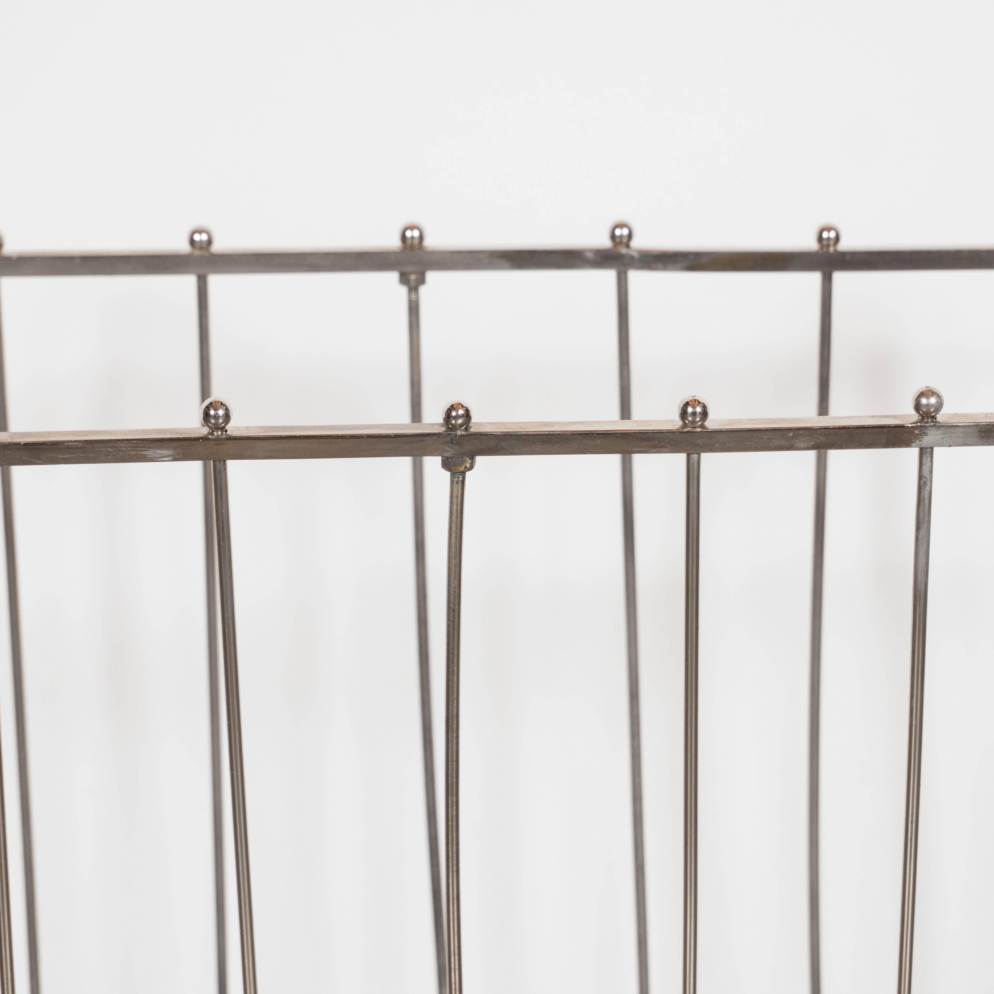 A Mid-Century Modernist nickel ribbed magazine stand with an interesting streamlined ribbed cradle shaped body decorated with ball finials. This Machine Age sculptural magazine rack is constructed as a single stylish unit complete with x shaped