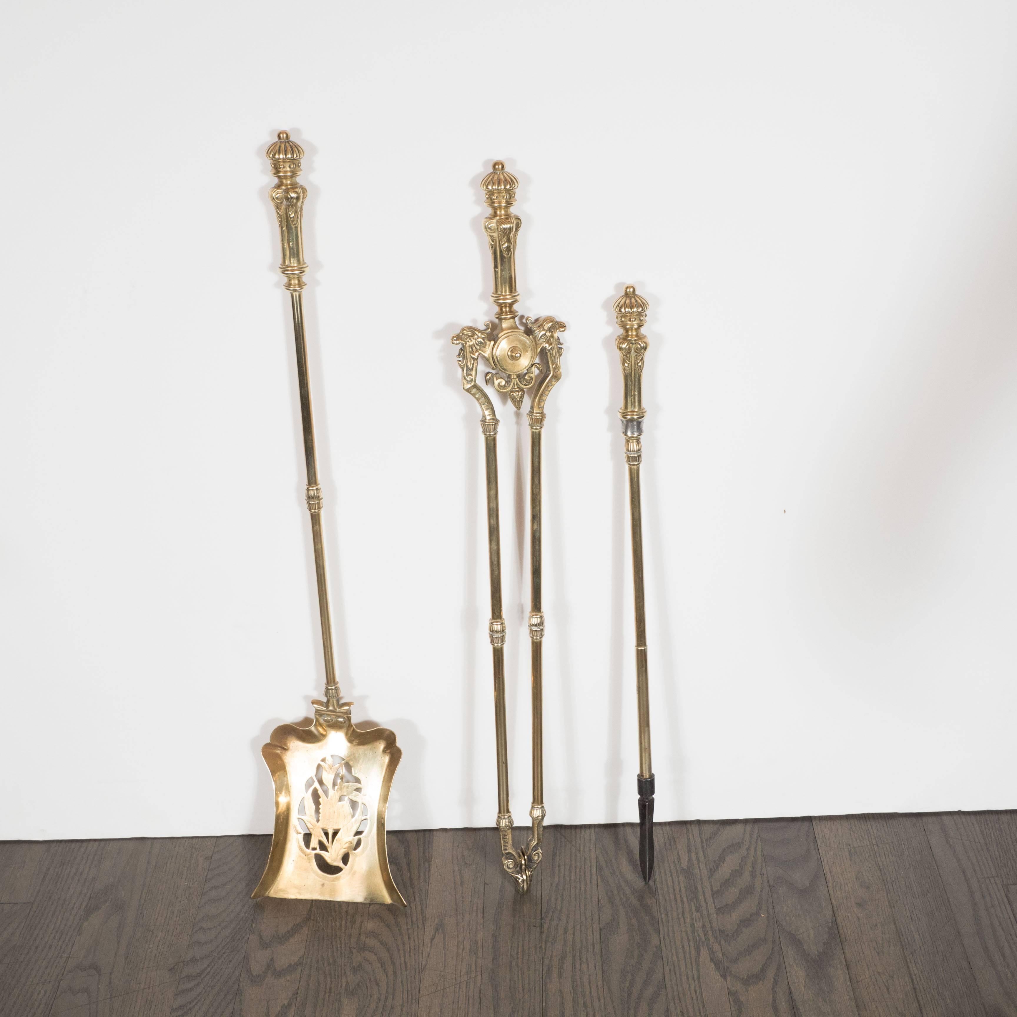 This refined antique brass fire three piece tool set was realized by hand in France, circa 1900. The set is comprised of a shovel, fire tongs and poker that fit neatly into a central stand- all hand fabricated in polished brass featuring