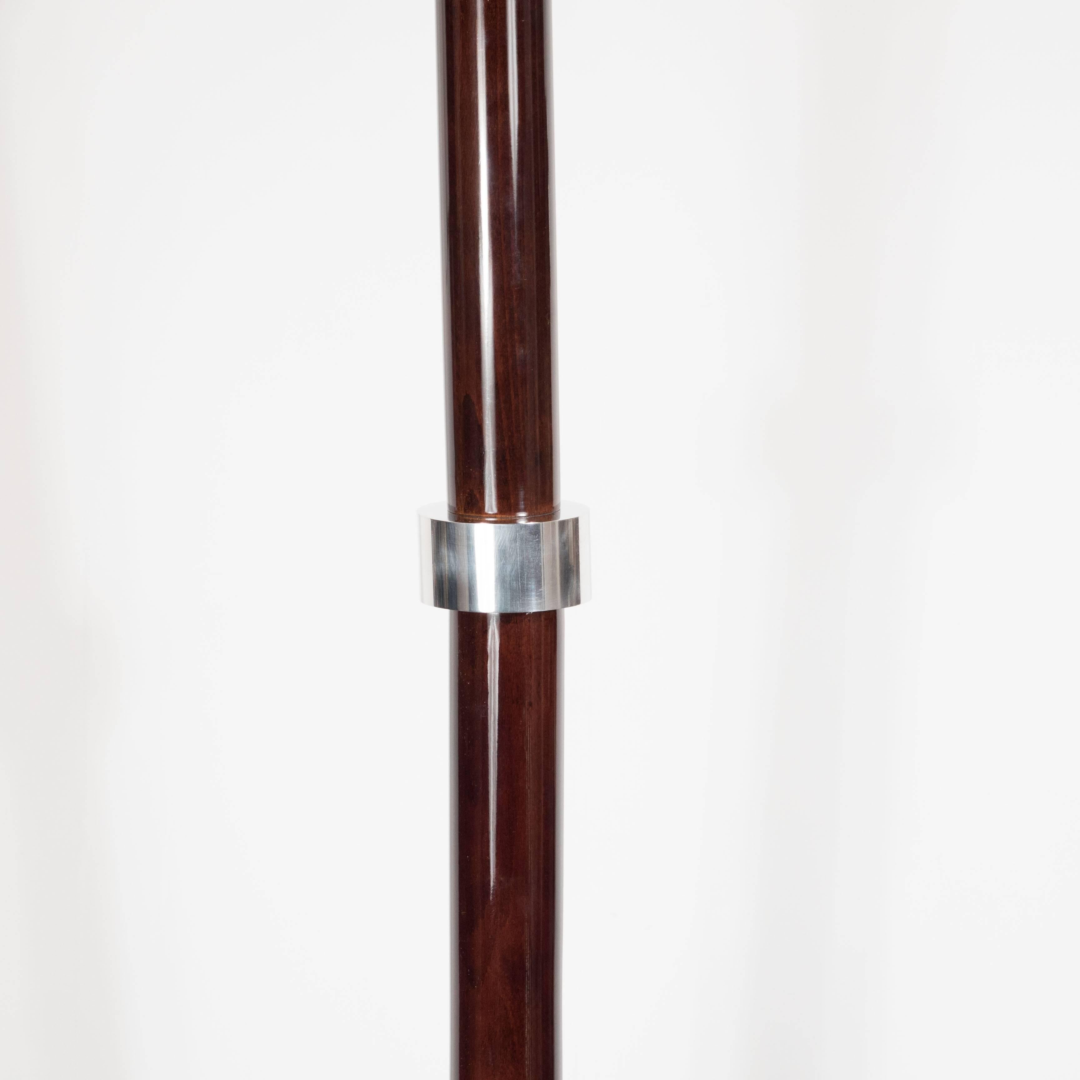 Created in France circa 1935, this luxe skyscraper style Art Deco torchiere lamp has been beautifully crafted in mahogany and polished chrome. It features a circular base, and a conical mahogany stem in mahogany with ringed chrome accents. The