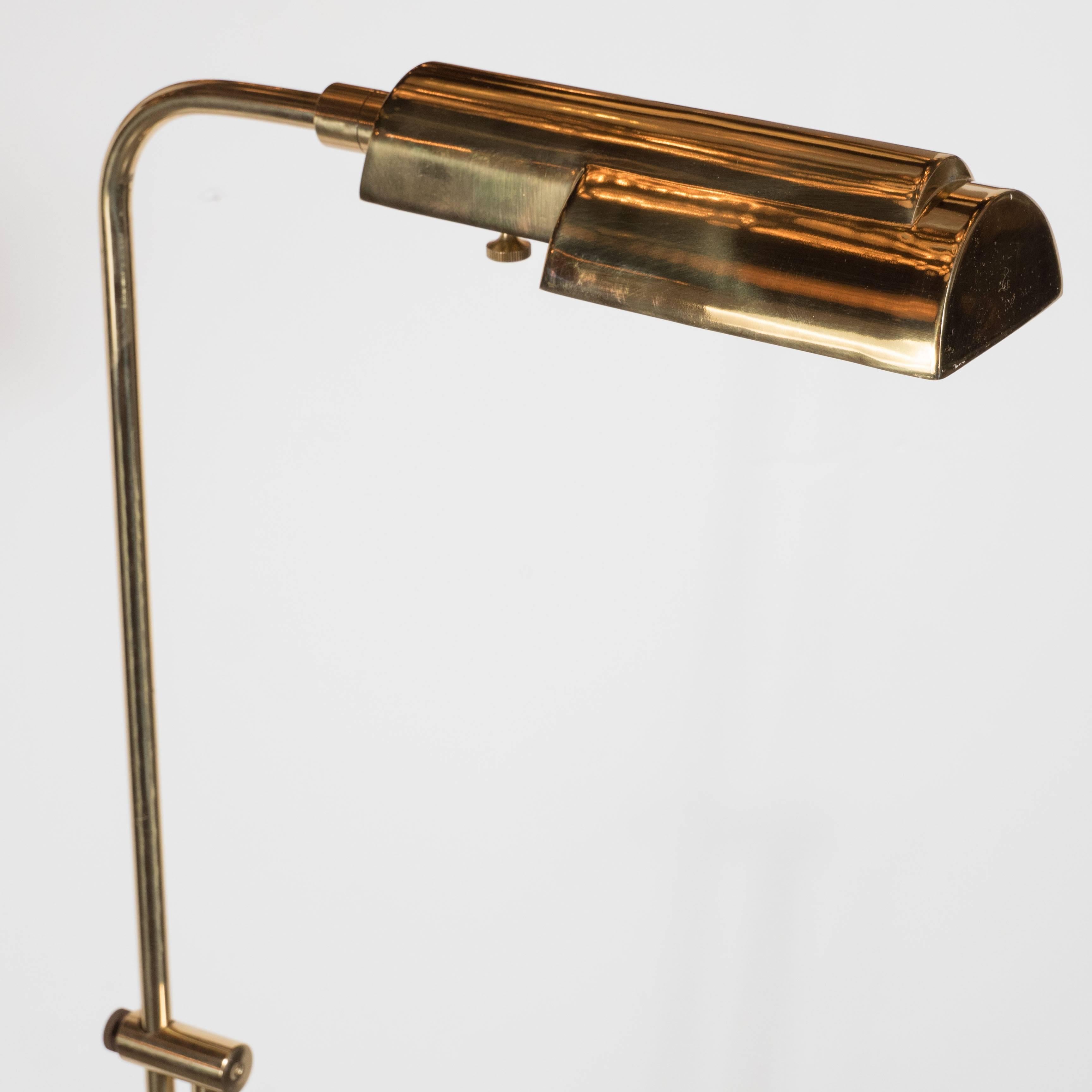 A Mid-Century Modernist brass adjustable floor lamp, this elegantly shaped extendable floor lamp attractively mounted on a circular brass base and sporting a charming hangover shade also made out of brass with the ability to swivel into various