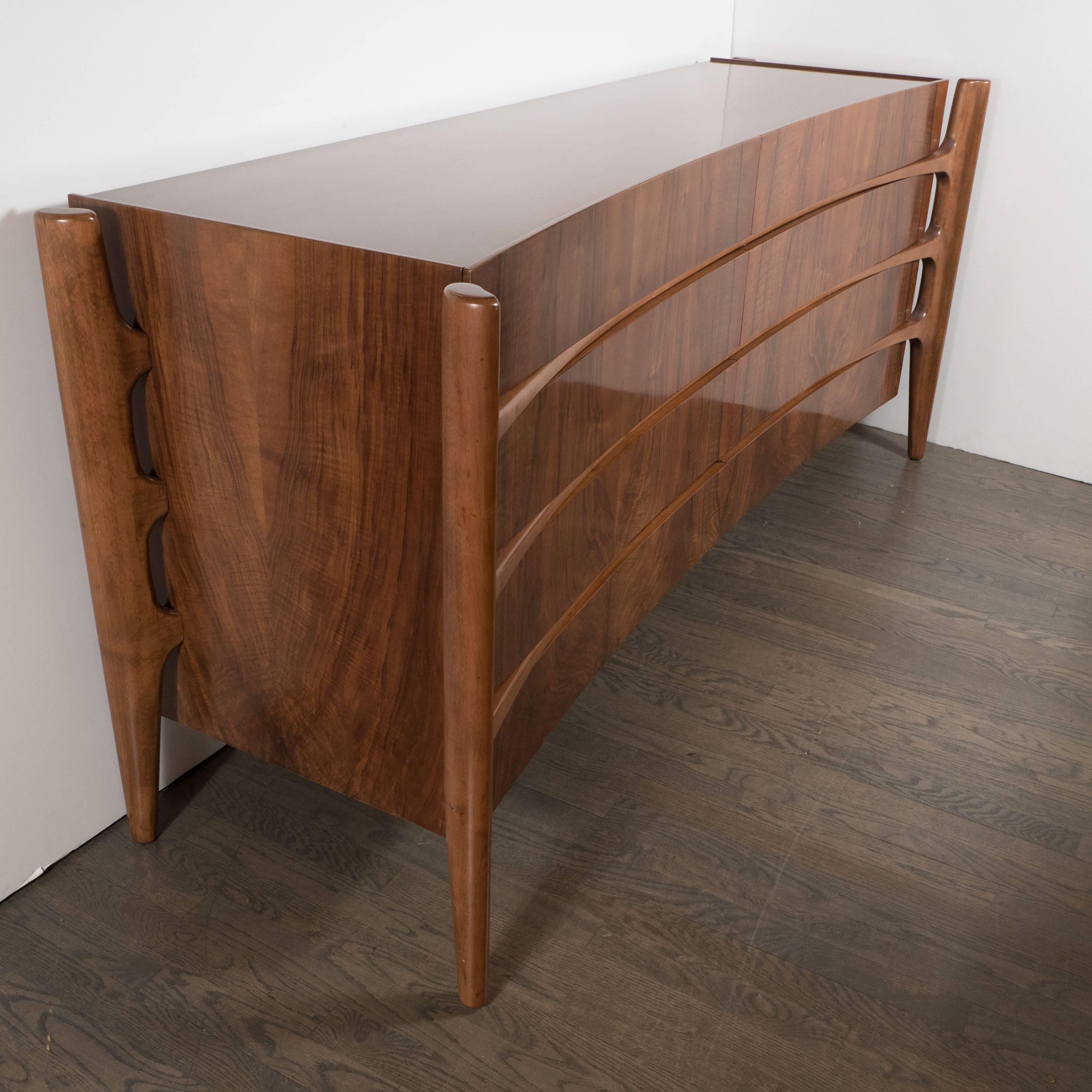 The celebrated Mid Century Modern Swedish designer William Hinn realized this exceptional and rare eight-drawer walnut dresser circa 1950. It features four splines, detached from the body of the cabinet, that descend into tapered legs. The splines