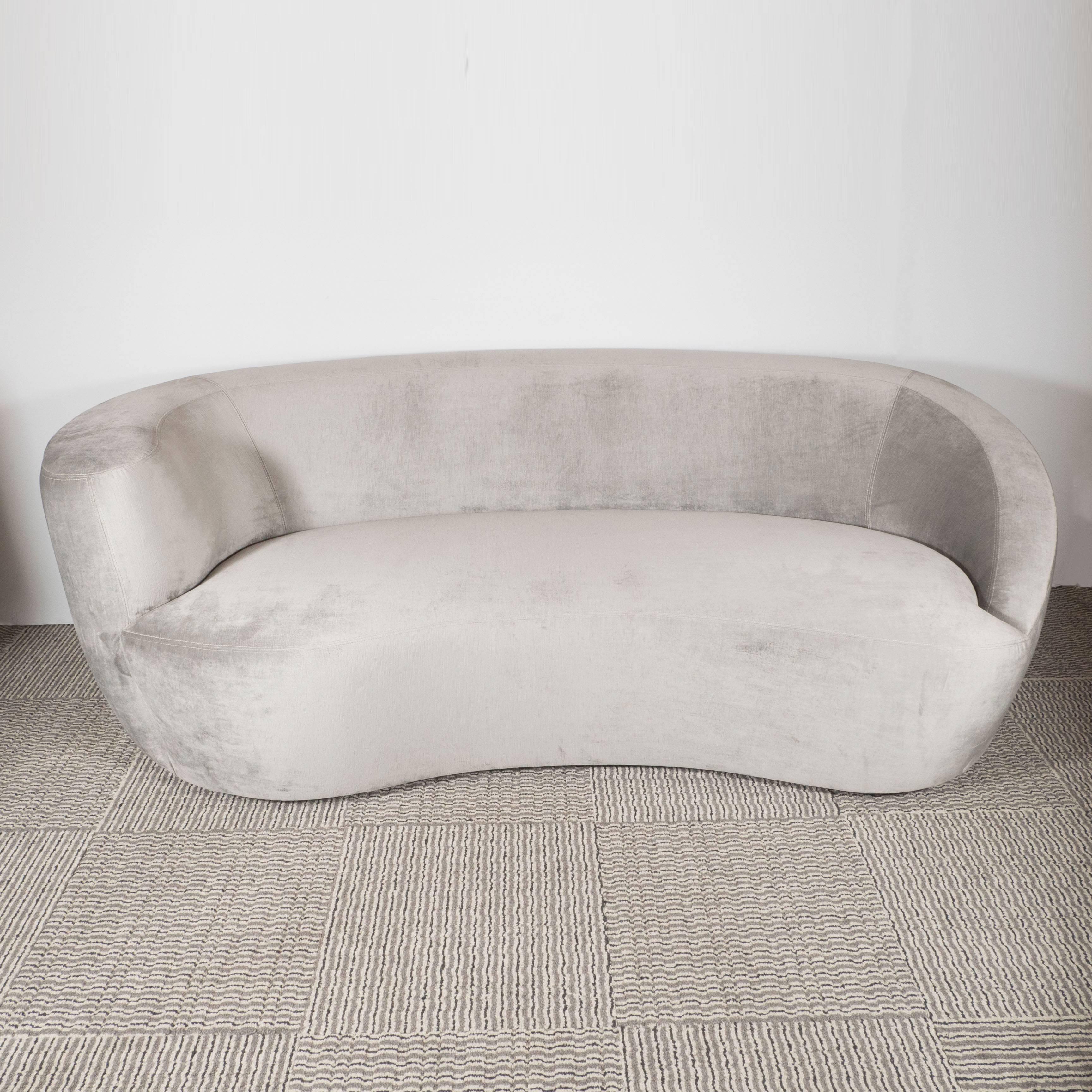 A Mid-Century modernist nautilus sofa by Vladimir Kagan. A bulbous, curved back and wraparound design lends to a clean, seamless aesthetic. A wide, continuous armrest slopes downward in a curved fashion. Entirely covered in a luxe smoked platinum