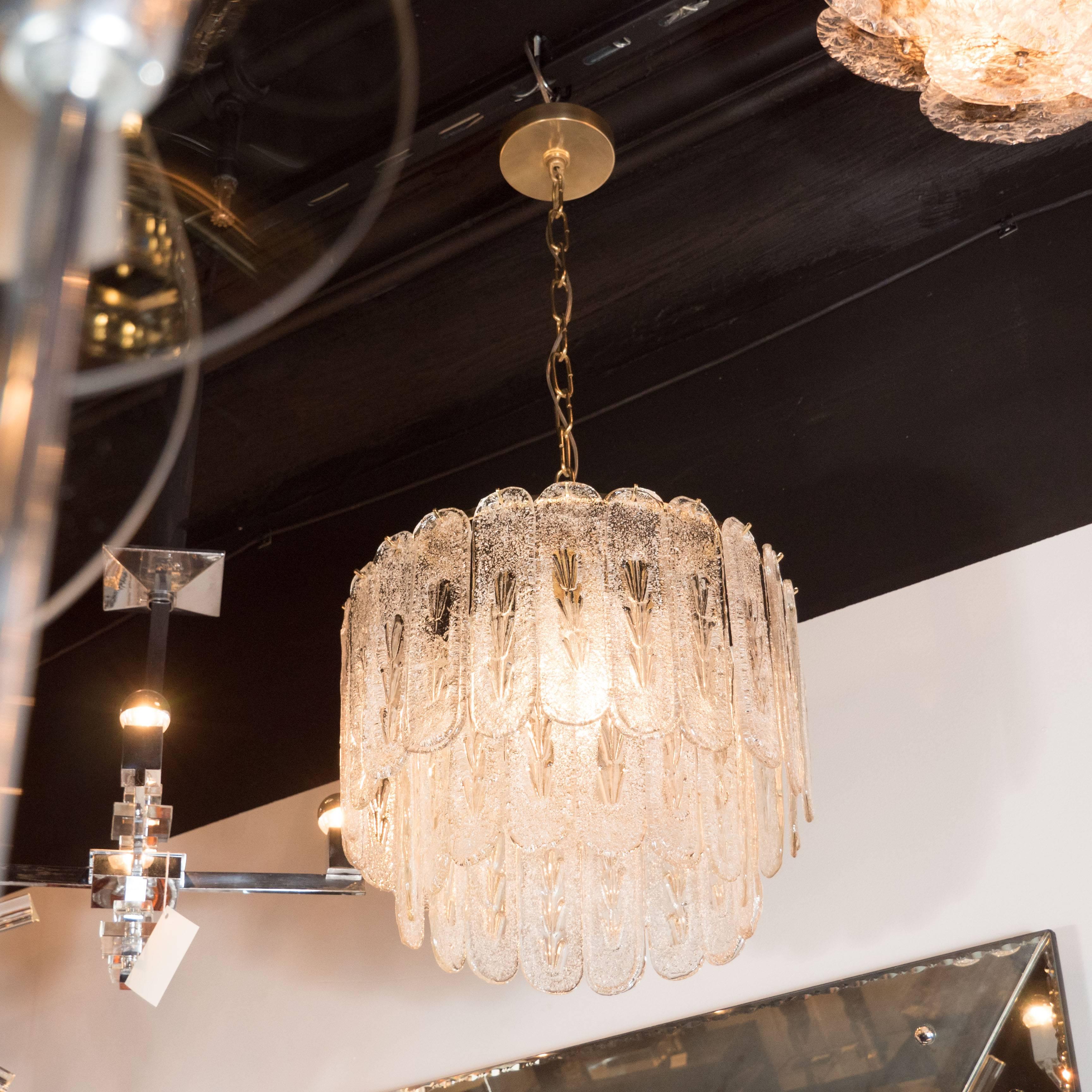 A chic Mid-Century Modernist two-tier Murano oblong textured glass disc chandelier, the handblown Murano oblond textured glass discs are individually hung across two concentric tiers, forming an elegant, flowing aesthetic. Brass fittings and