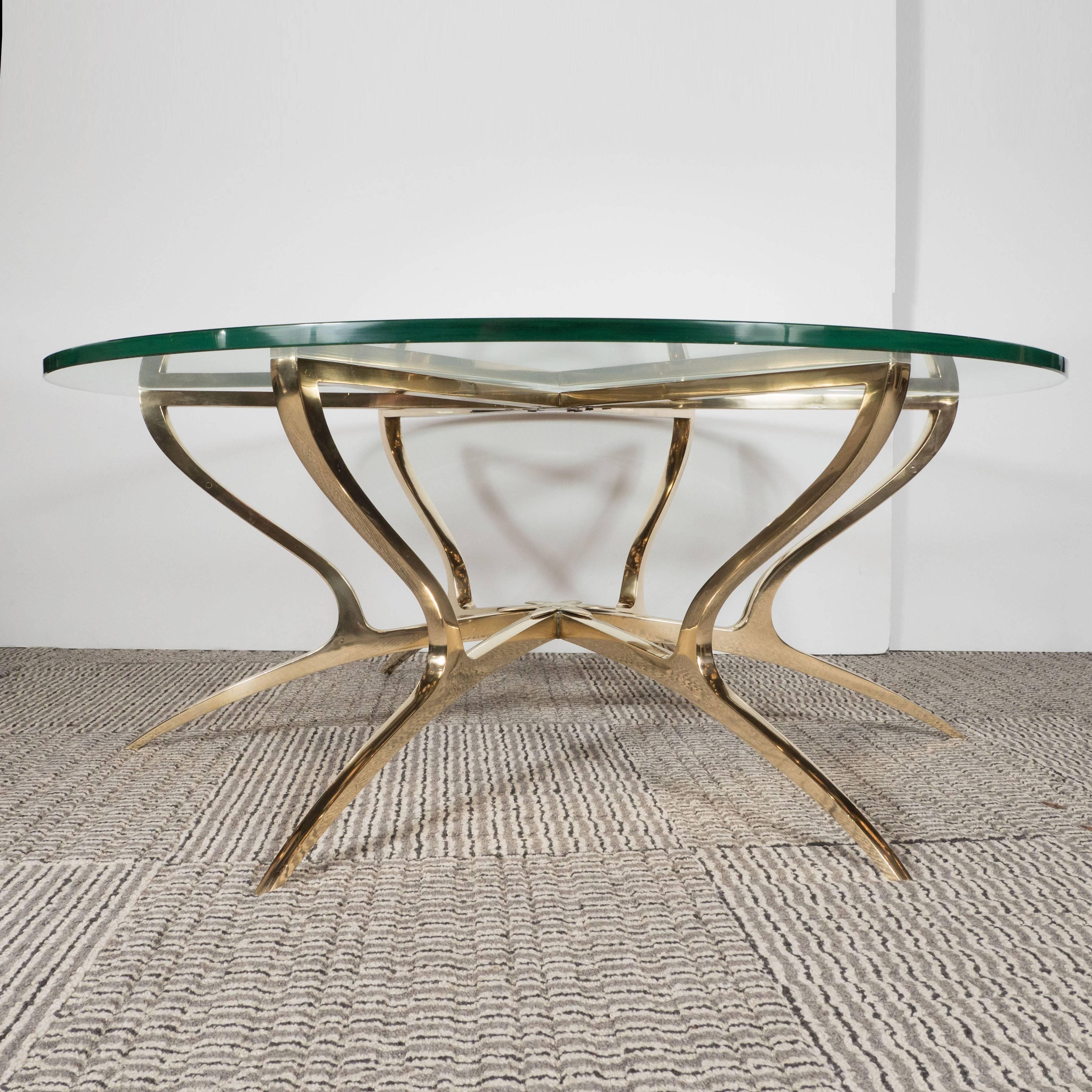 Created in Italy, circa 1970, this sculptural cocktail table features six solid brass saber legs. They extend from a central base adorned with a stylized lotus blossom. A curvilinear support extends from each leg, meeting straight arms at a