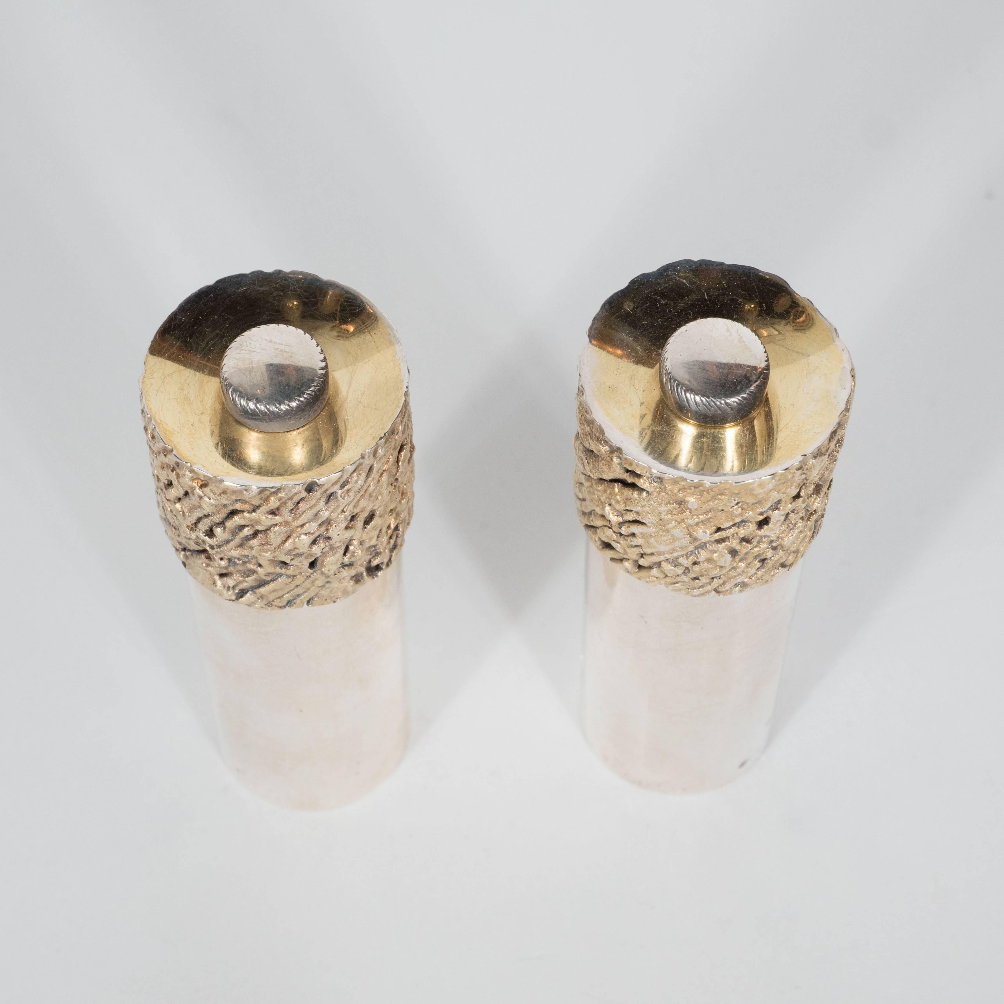 These very beautiful salt and pepper grinders are sterling silver and cylindrical in form with a Brutalist turning top in 18-karat gilt. They have English Hallmarks and marked SD as well. I have never seen anything quite like them and they are not