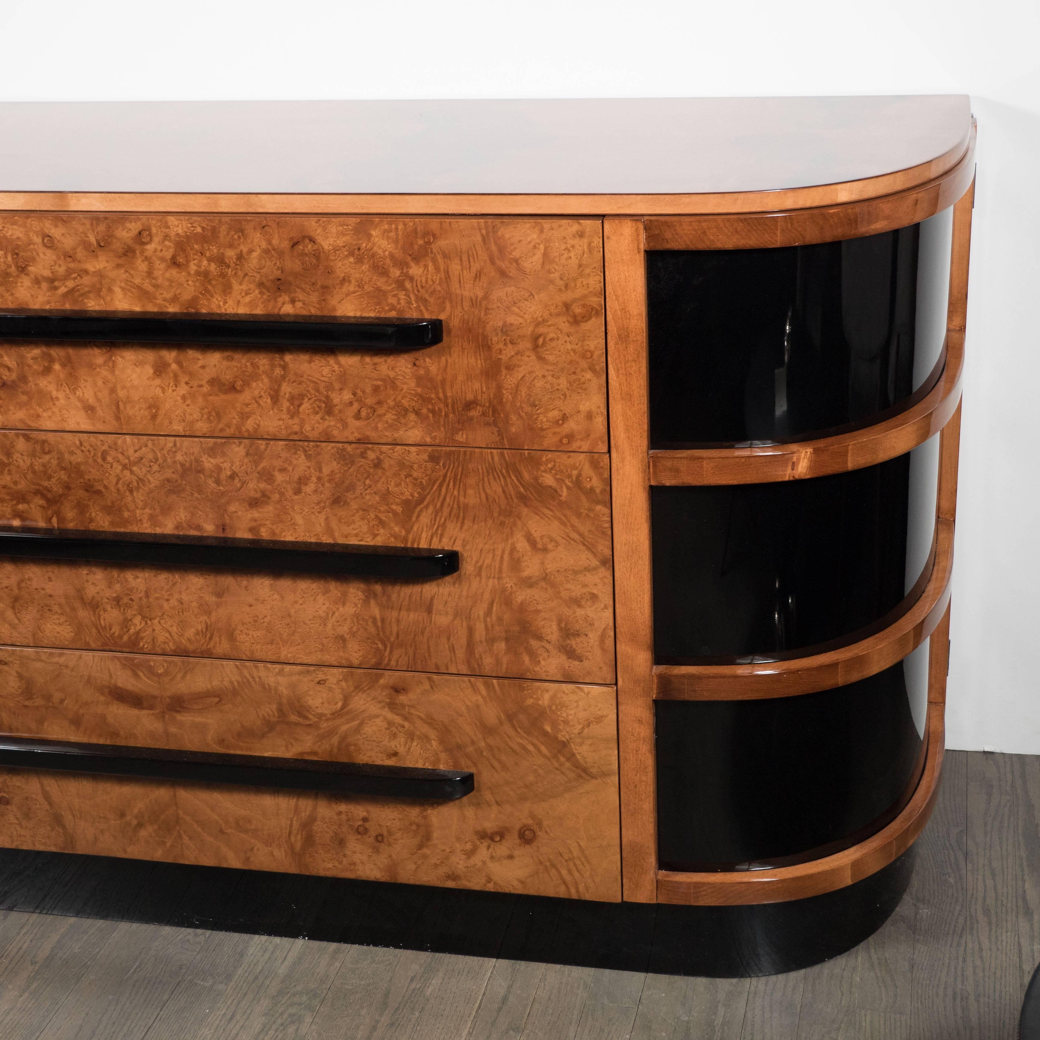 This is a really beautiful sideboard or console cabinet designed by Walter Darwin Teaque for Hastings Co. It is exotic book-matched burled walnut with black lacquer accents and polished aluminum trim. The finish is high gloss hand polished lacquer.