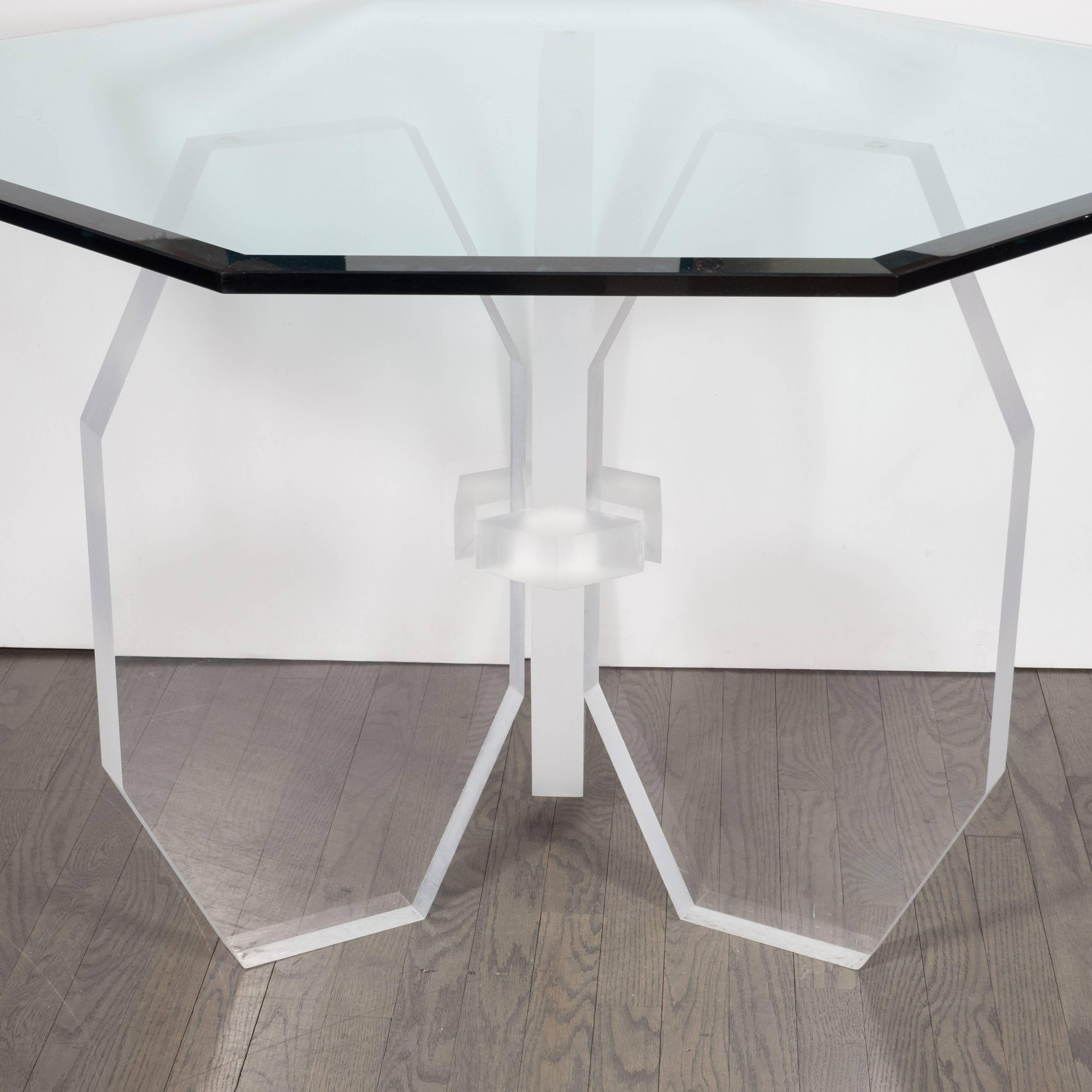 A Mid-Century modernist dining table with a sculptural base consisting of three octagonal faceted panels pinned together by a center piece of frosted Lucite. The faceted design of the base is emulated in the octagonal beveled glass tabletop. Being