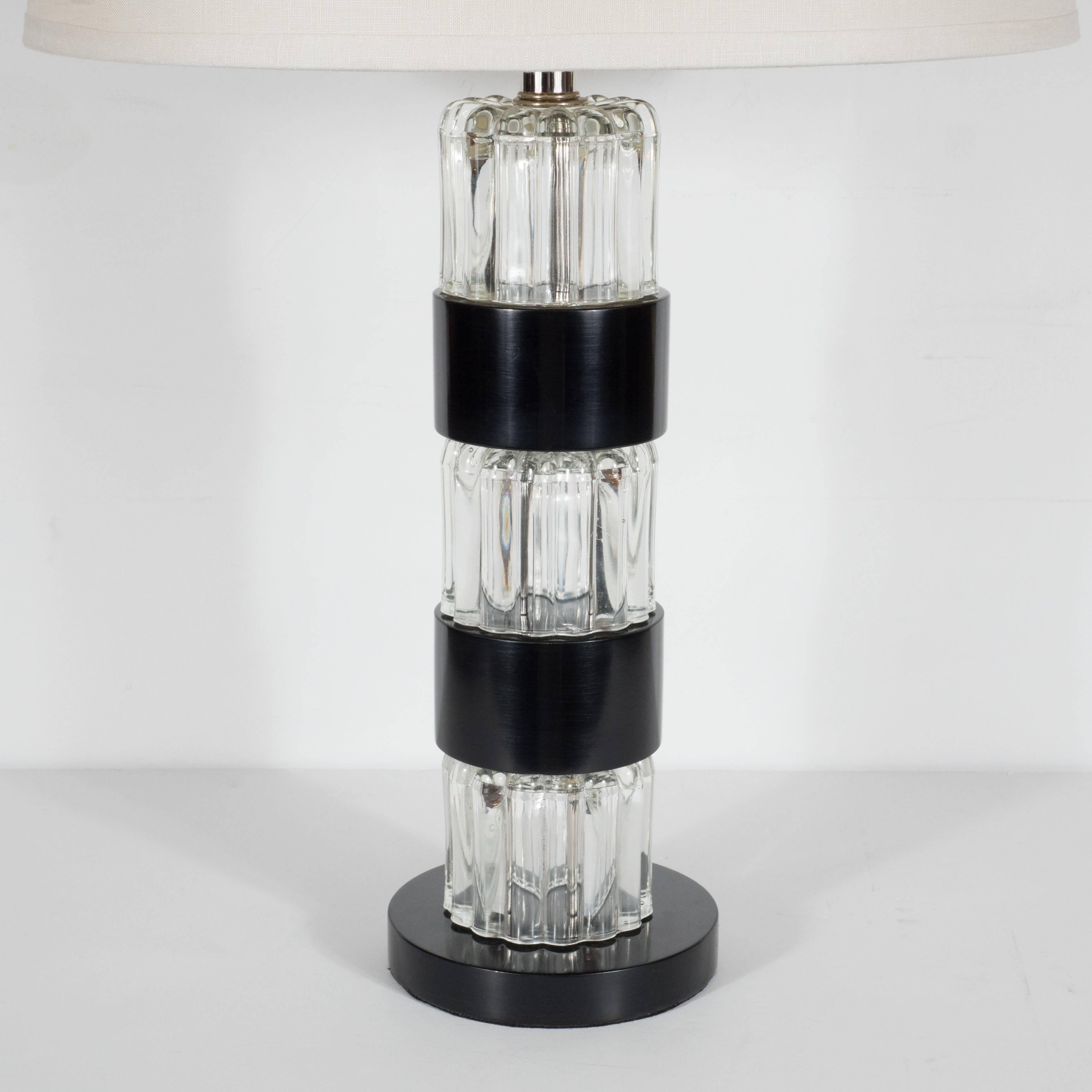 Striking Mid-Century Modern pair of table lamps by Russel Wright, attractively designed with bands of ebonized walnut separating the circular glass base itself which is composed of pressed glass creating an interesting transparent pattern. The base