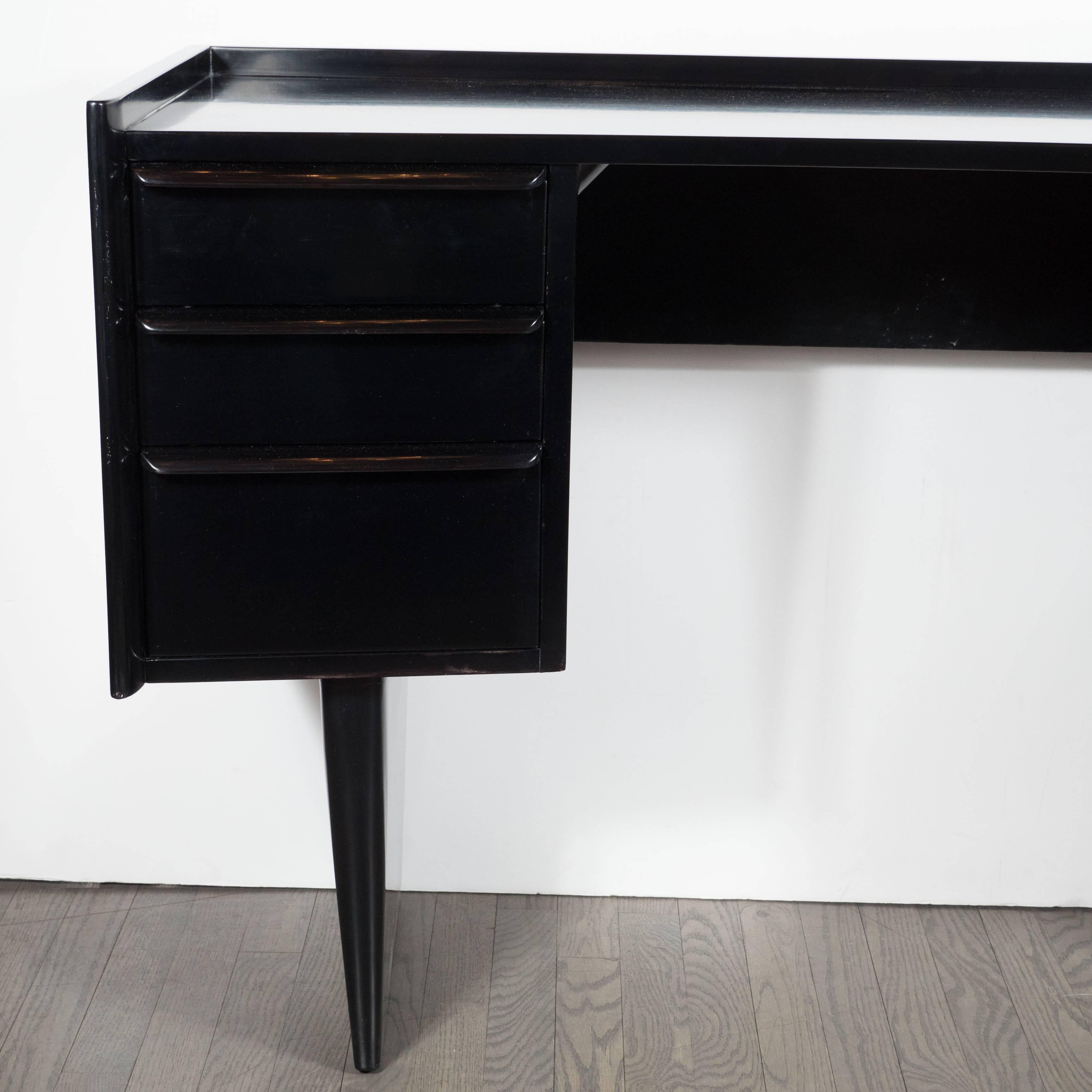 Mid-Century modernist Streamlined bowed-front desk or vanity in hand-rubbed ebonized walnut. A pair of deep, slightly tapered legs support a curved-front desk with a total of six pull-drawers. It features a hand-rubbed finish in ebonized walnut. Its