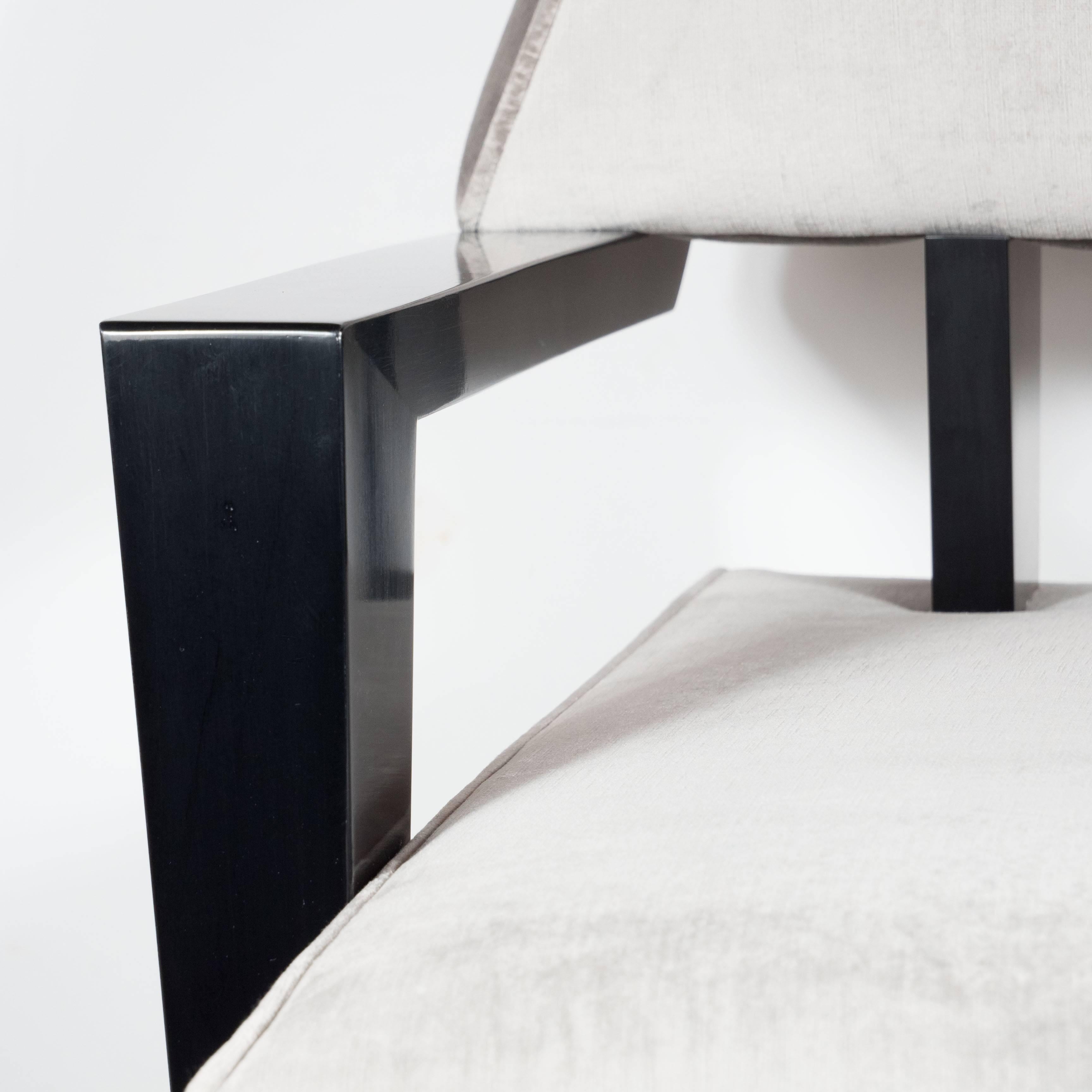 A bold pair of Mid-Century sculptural armchairs in smoked platinum velvet, in the style of James Mont. Wide, deep bases connect to a tapered headrest by two ebonized walnut supports. The wide armrests and front legs are also hand-rubbed ebonized