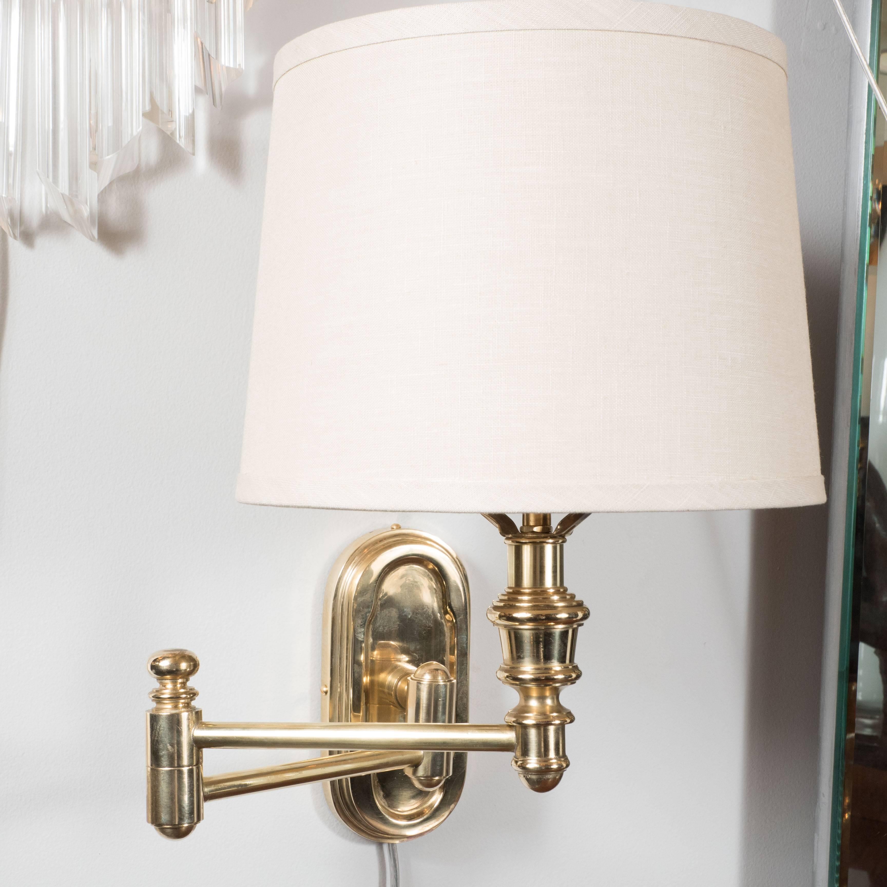 These very elegant swing arm sconces feature an oval back plate all made of solid high quality brass. They also feature a custom off-white linen shade with original brass finial. The arm extends generously to provide fa variety of positions. They