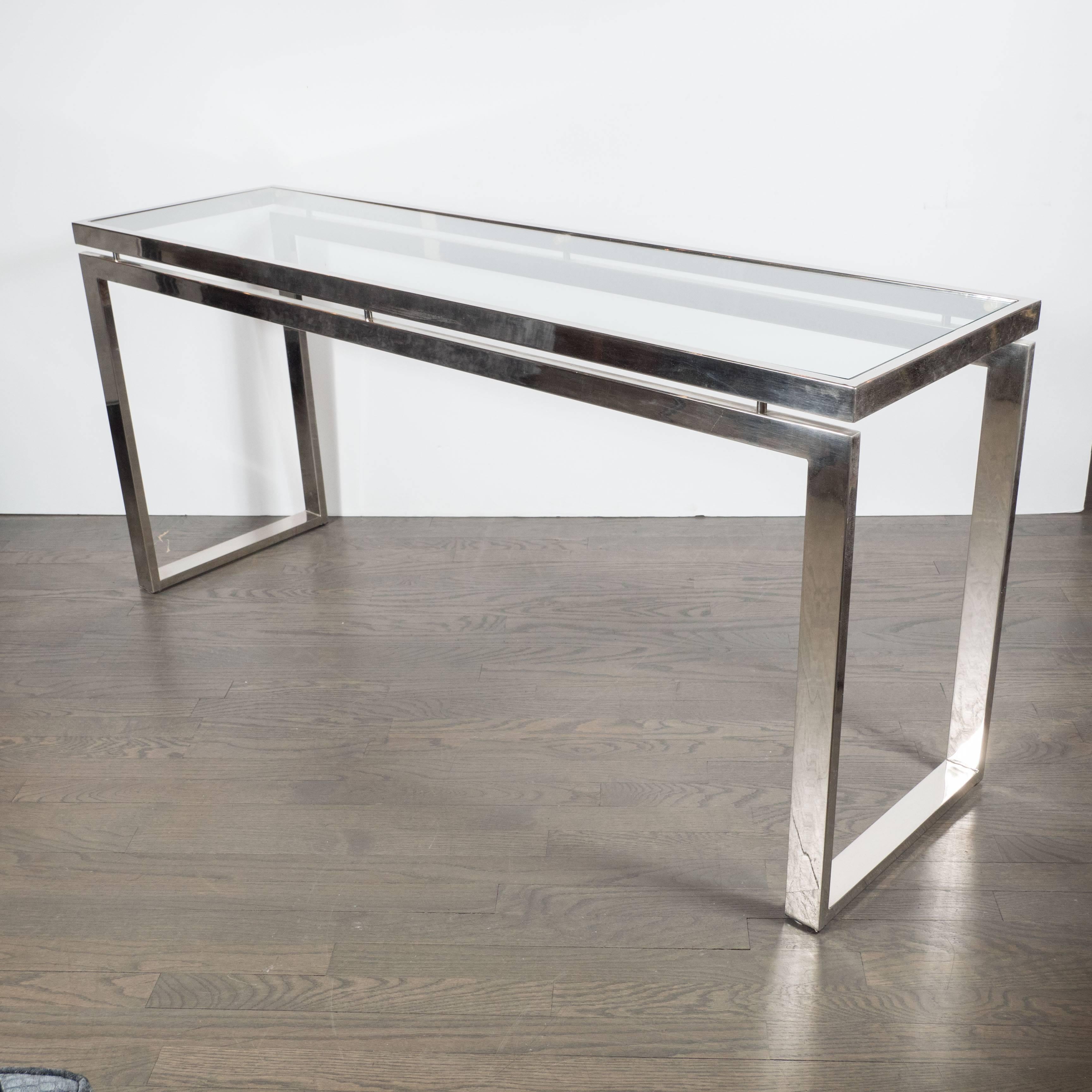 This very sleek Mid-Century Modernist chrome and glass console or sofa table features a sleek and stylized chrome base that supports a glass top. The rectangular glass top has a chrome surround resting on chrome supports giving the piece a light and