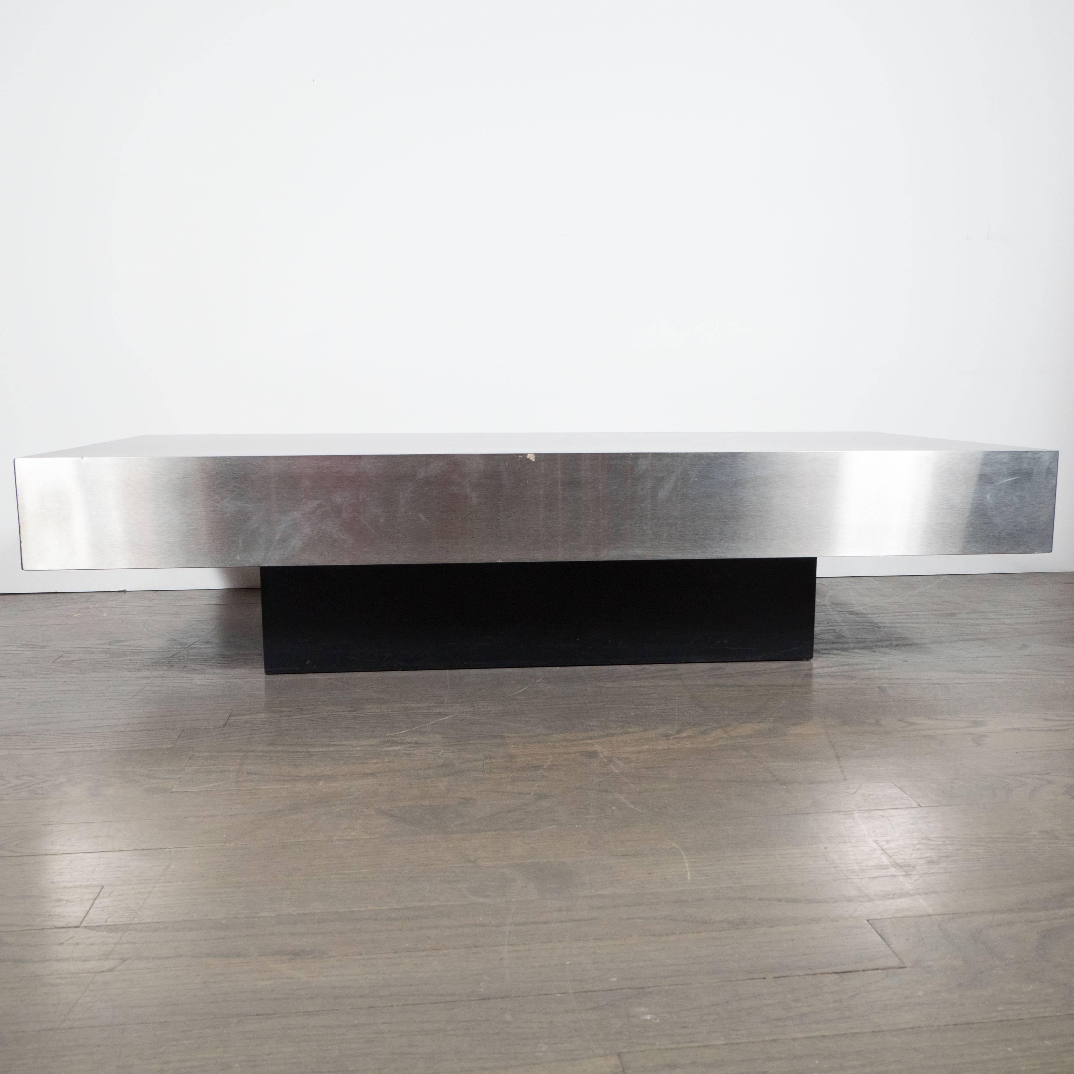 A Mid-Century modernist low rectangular cocktail table in brushed aluminium in the style of Breuton. Brush aluminium panels cover the sides of the piece while the top is a black laminate. The base is ebonized walnut. A Minimalist, clean cocktail