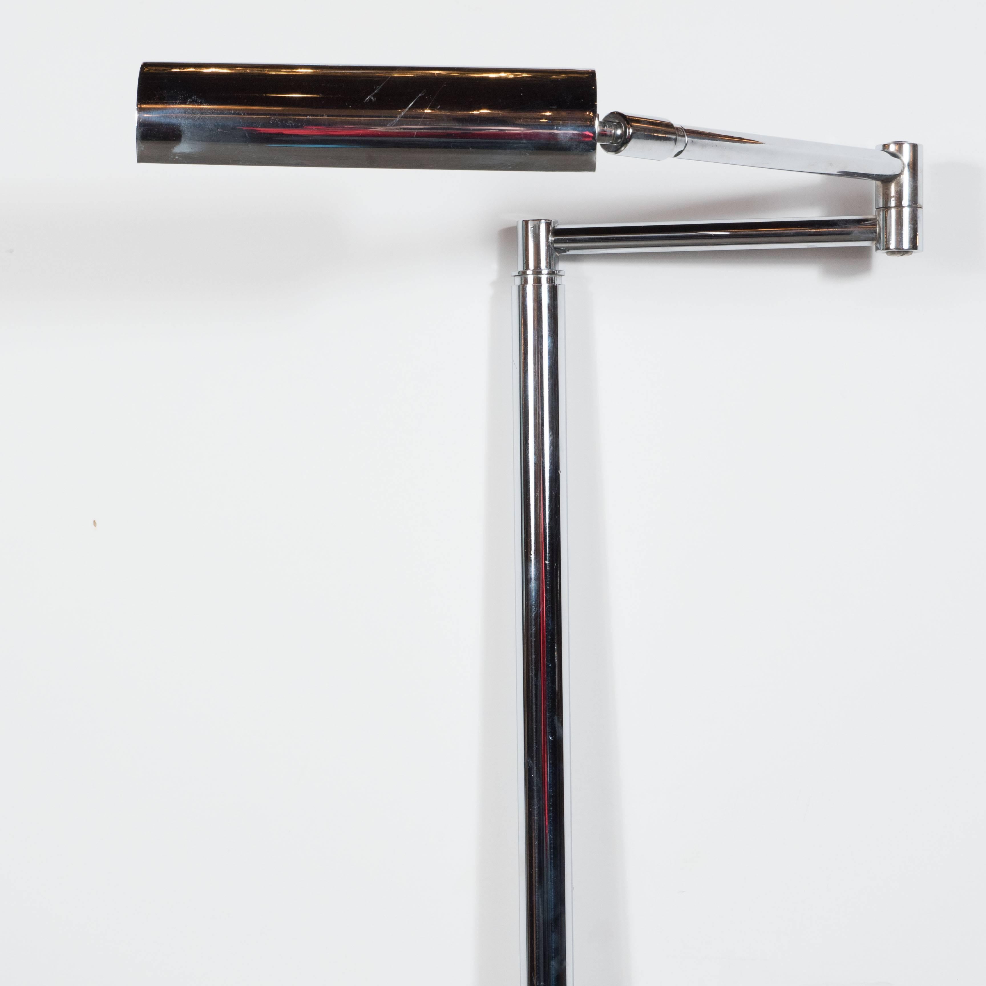 Ce lampadaire à bras pivotant de style moderne du milieu du siècle présente une base ronde chromée minimaliste et un abat-jour cylindrique pouvant pivoter dans différentes positions ; idéal pour la lecture en fauteuil ou le bureau. Ce luminaire a