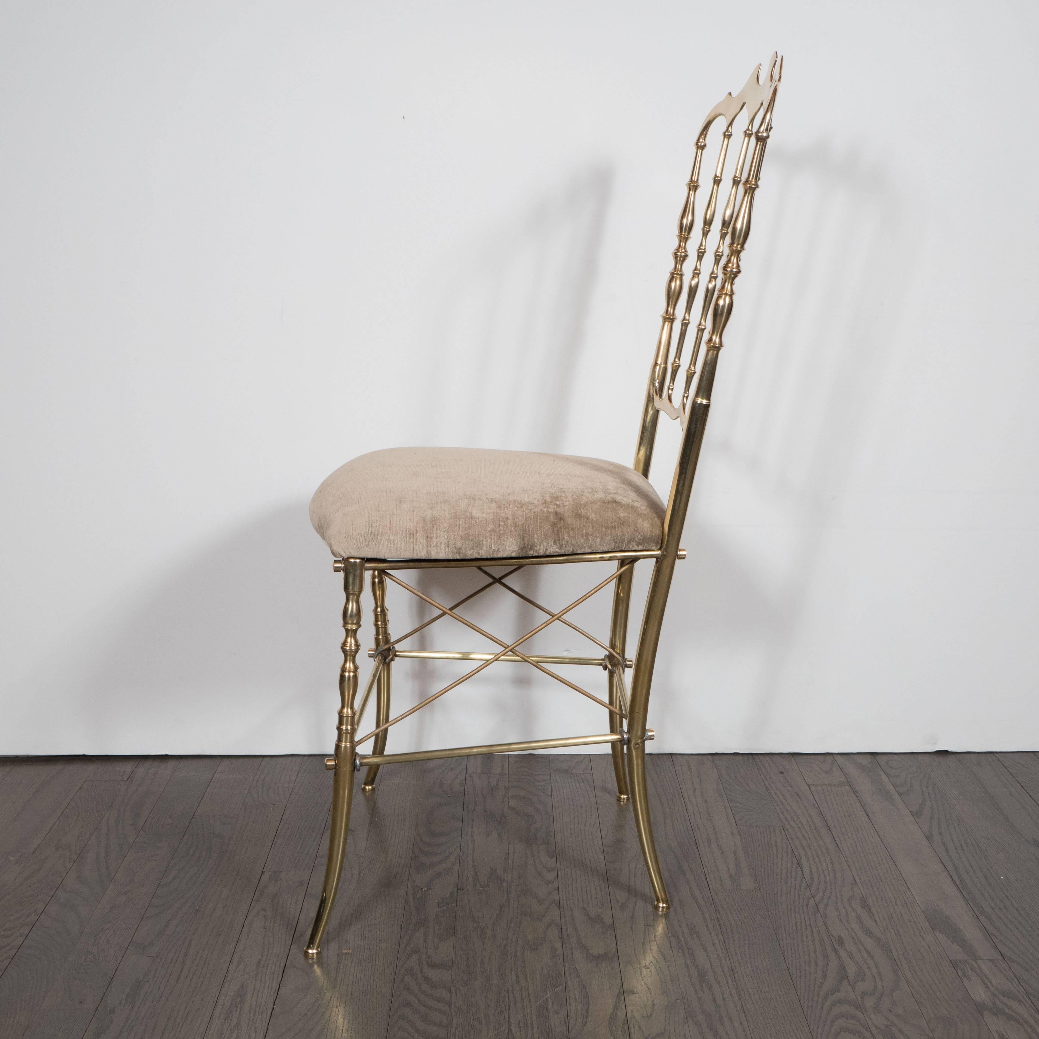 A Mid-Century modernist brass chair by Chiavari in smoked champagne velvet. Slightly splayed legs connected with pairs of cross-supports, all in polished brass, support a newly upholstered seat cushion in a luxe smoked champagne velvet. The