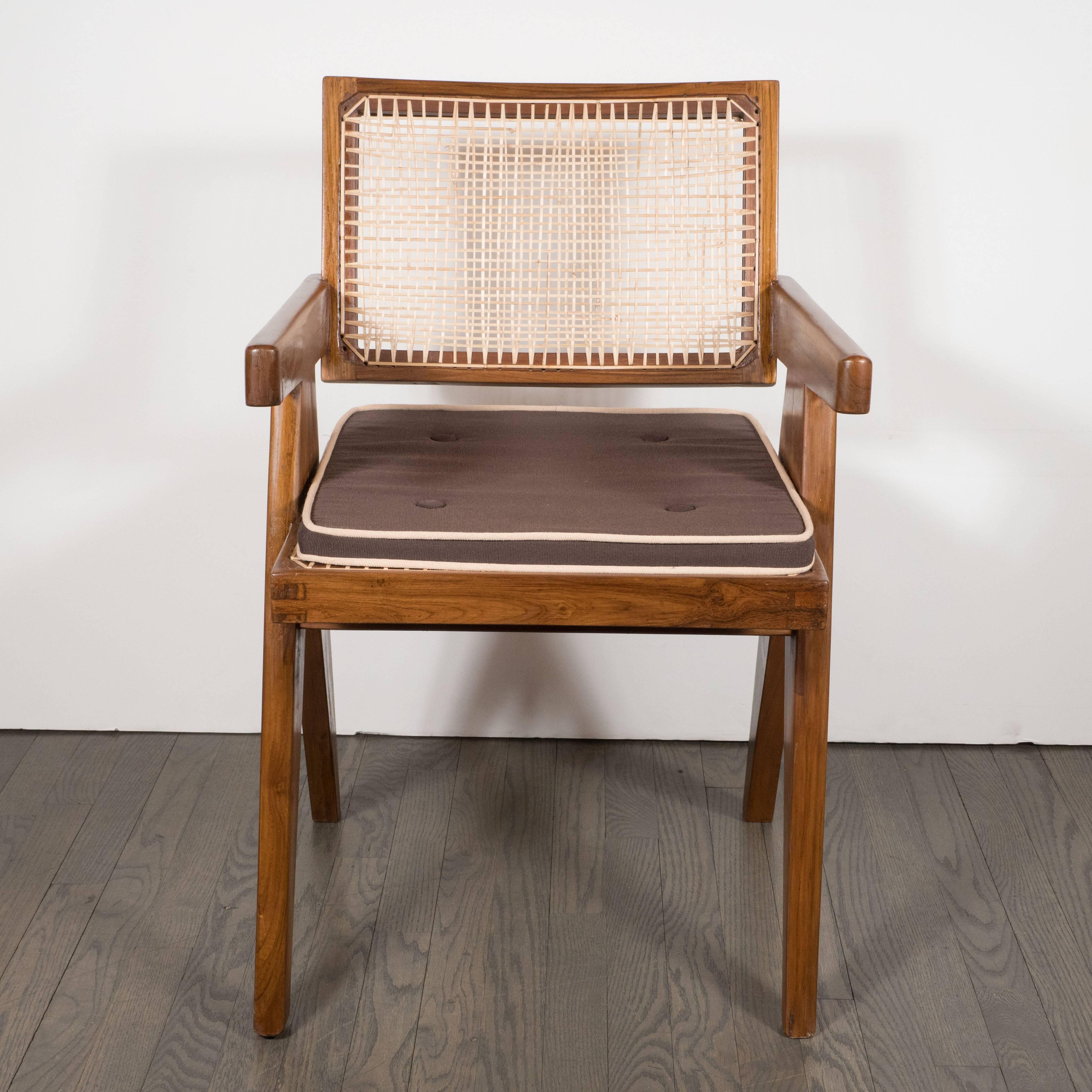 A pair of Mid-Century modernist armchairs in teak, caning and upholstery by Pierre Jeanneret, from the Chandigarh administrative buildings, model PJ-SI-28-A. A caned seat and seat-back is supported by solid teak mortis and tenon frame. Splayed legs