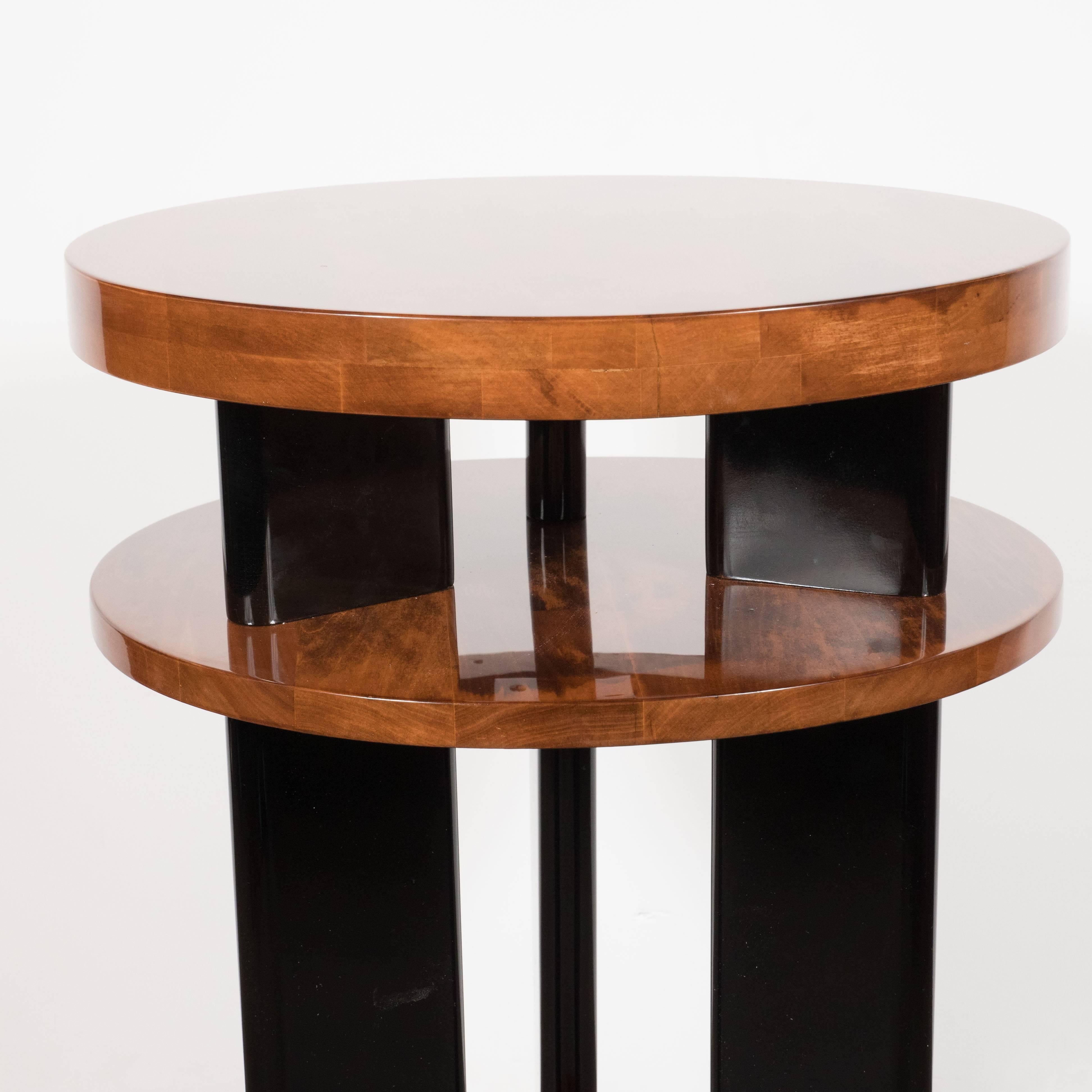This Art Deco Machine-Age Gueridon table features three tiers of bookmatched walnut supported black lacquer legs that extend to the floor. An embodiment of Art Deco Elegance, this occasional table would be equally well suited next to a chair or a