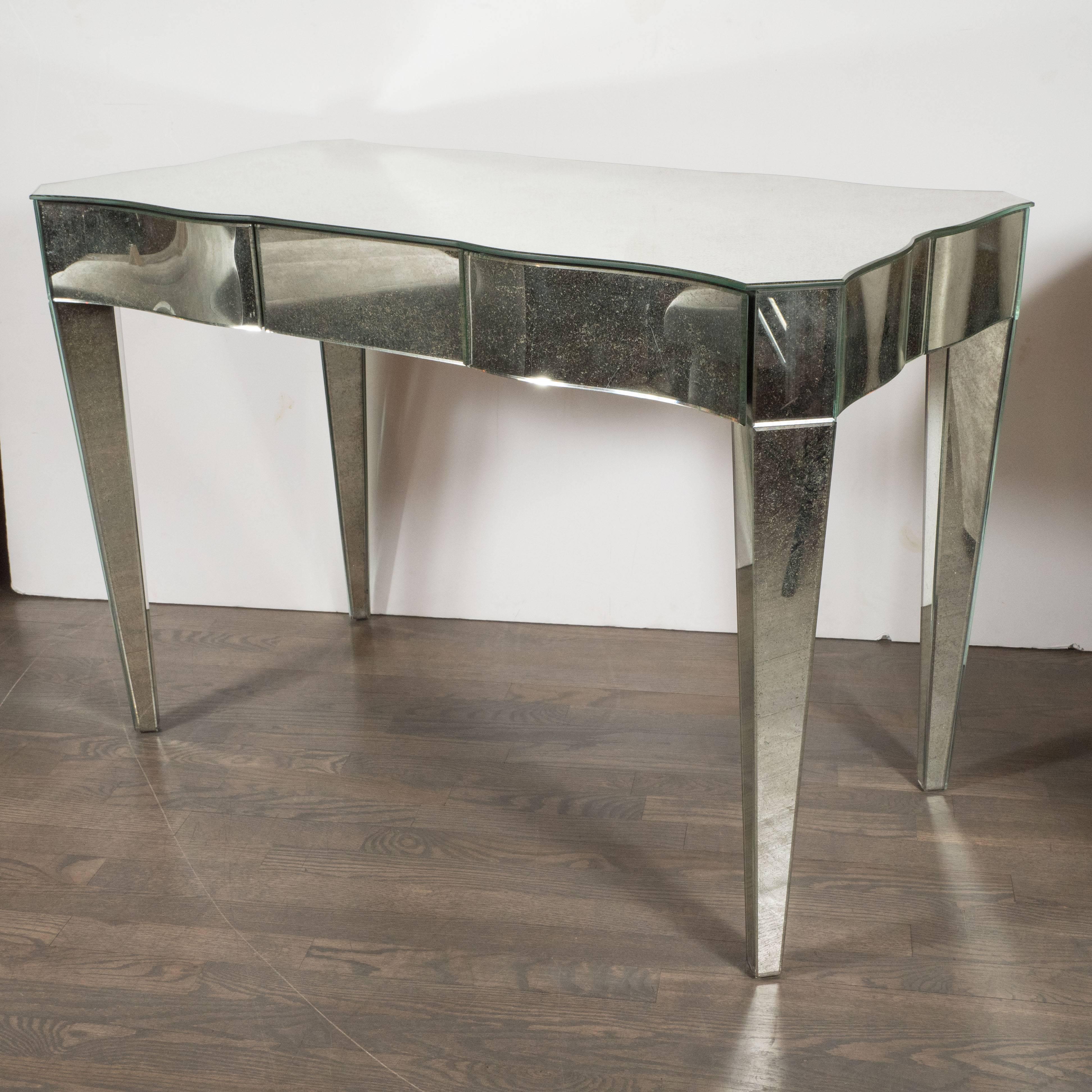 This mirrored vanity features serpentine beveled sides, squared corners and tapered 