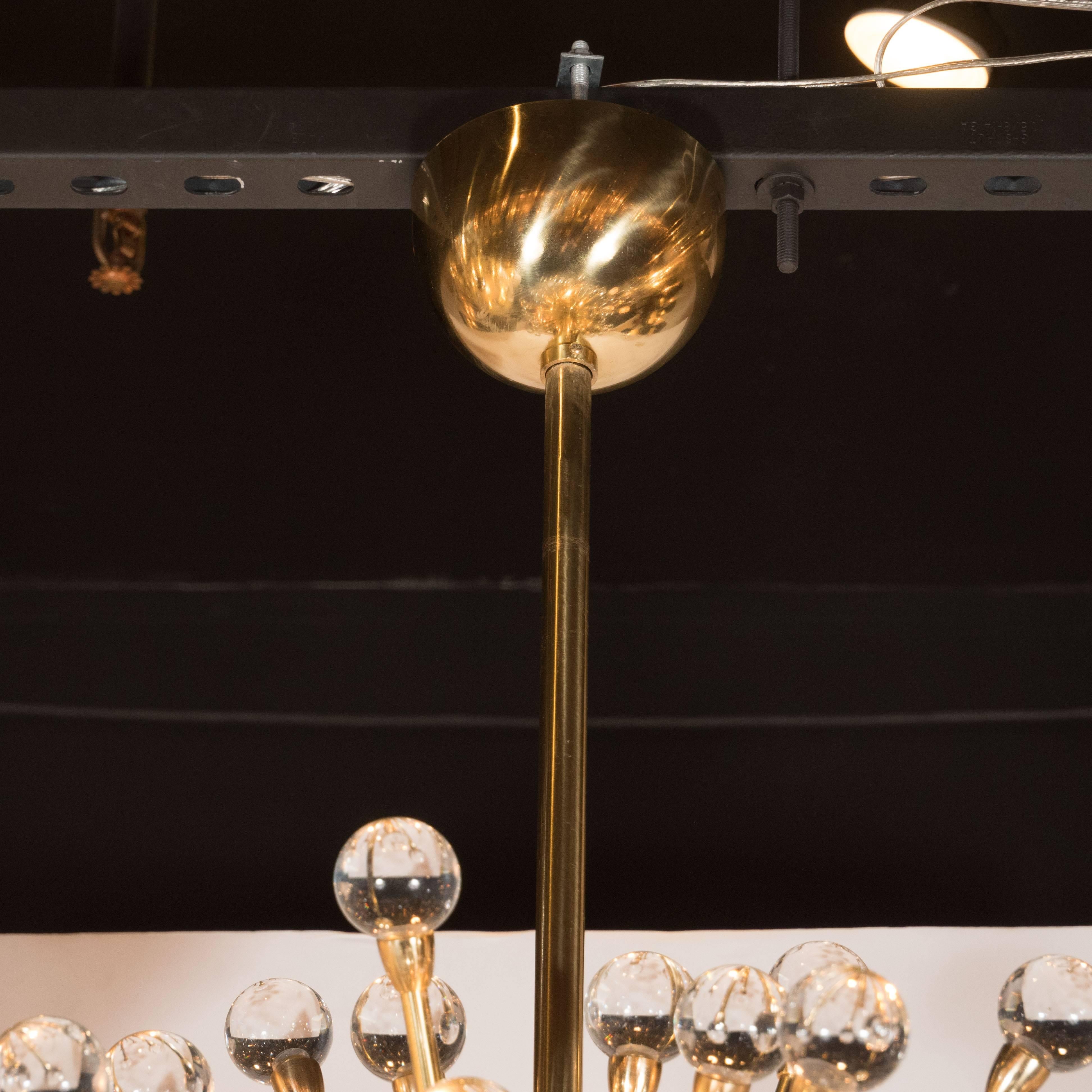 This dazzling and sophisticated crystal ball Sputnik chandelier features an exploding form with an abundance of polished brass arms capped with handblown crystal orbs. Realized by our exclusive atelier in Murano, Italy, this piece represents the