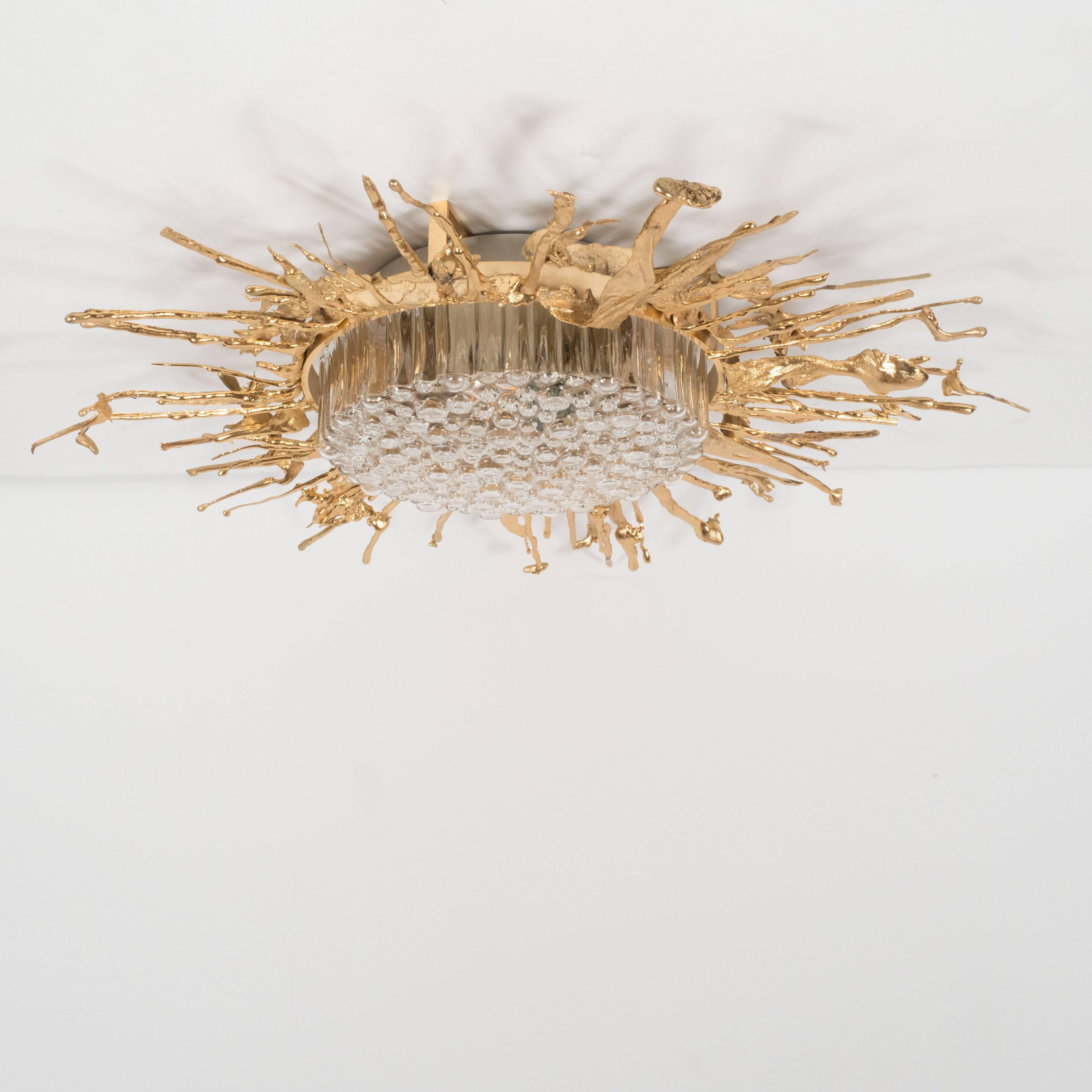 This stunning flush mount chandelier, handmade by the renowned French designer Claude-Victor Boeltz, features an explosion of organic forms rendered in gilded bronze and a smoked gray glass cover with an abundance of suspended bubbles. The fixture