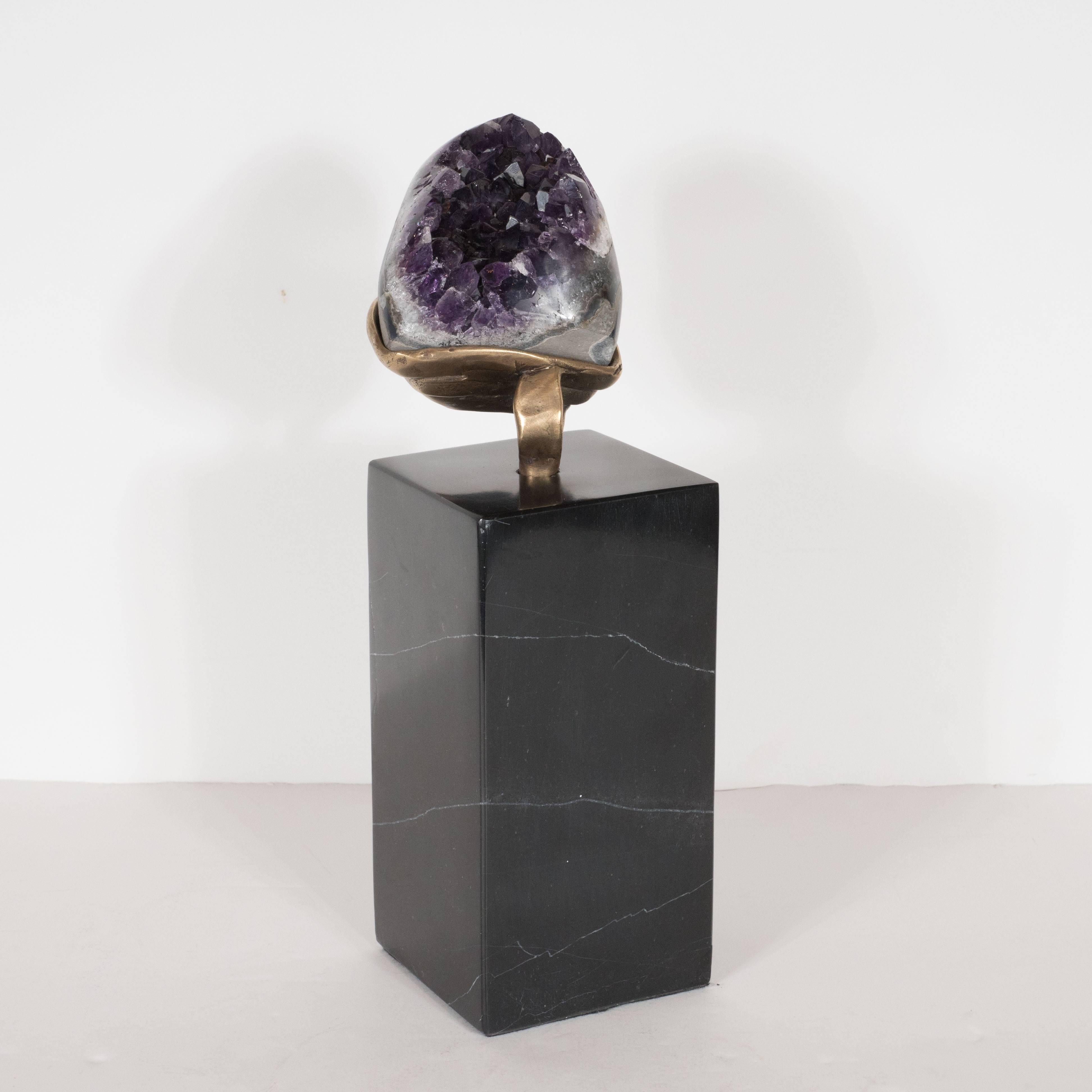 This striking amethyst offers a calyx of vibrant purple crystals. Since it is an exposed geode, its back consists of a quiet gray hue, while its interior reveals an explosion of shimmering color. It rests on a delicately handcrafted custom-made