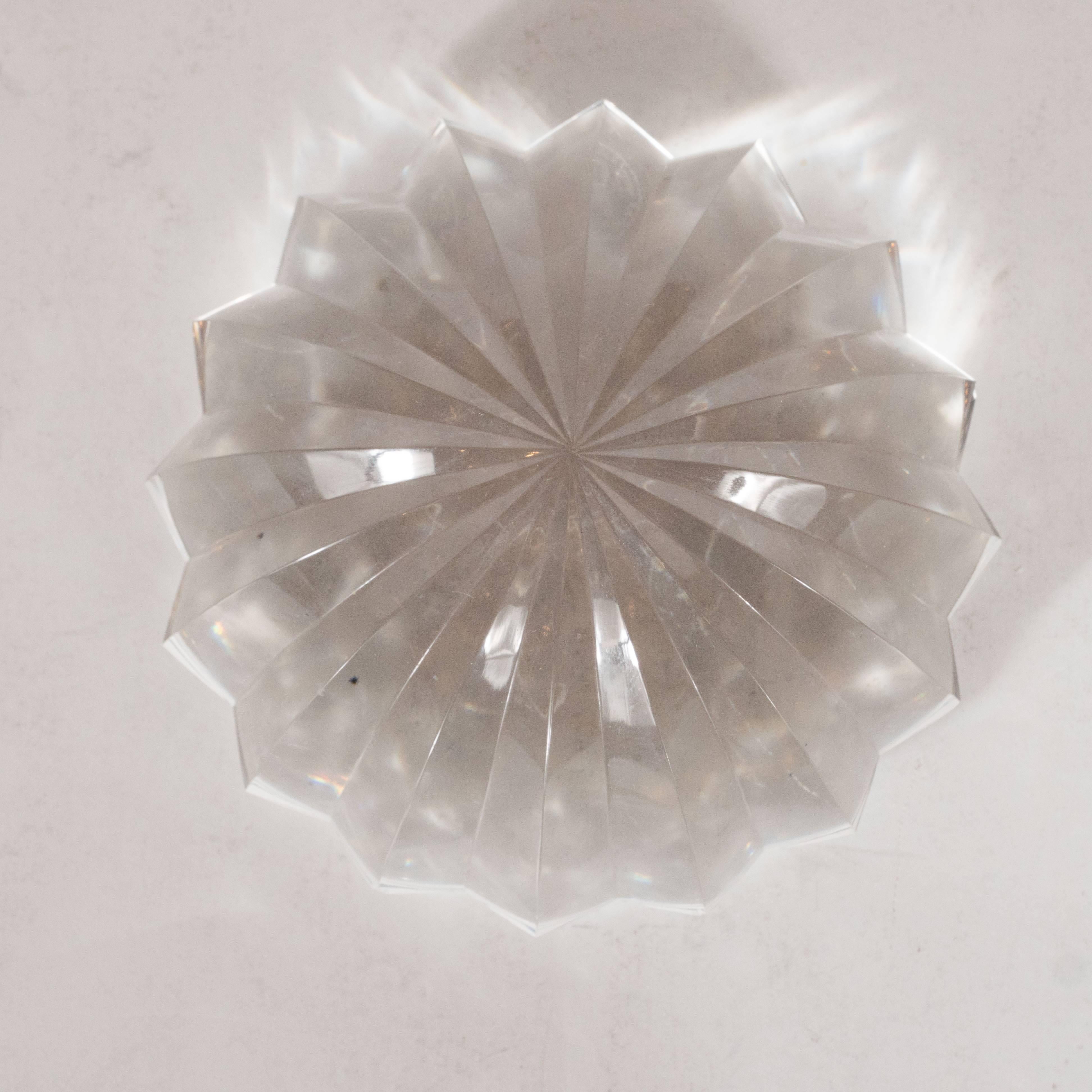 This stunning Mid-Century Modernist paperweight was realized circa 1970 by Baccarat, arguably the world's premiere crystal maker. Resembling a stylized sand dollar, it features an abundance of vaulted channels of cut crystal curving down to the