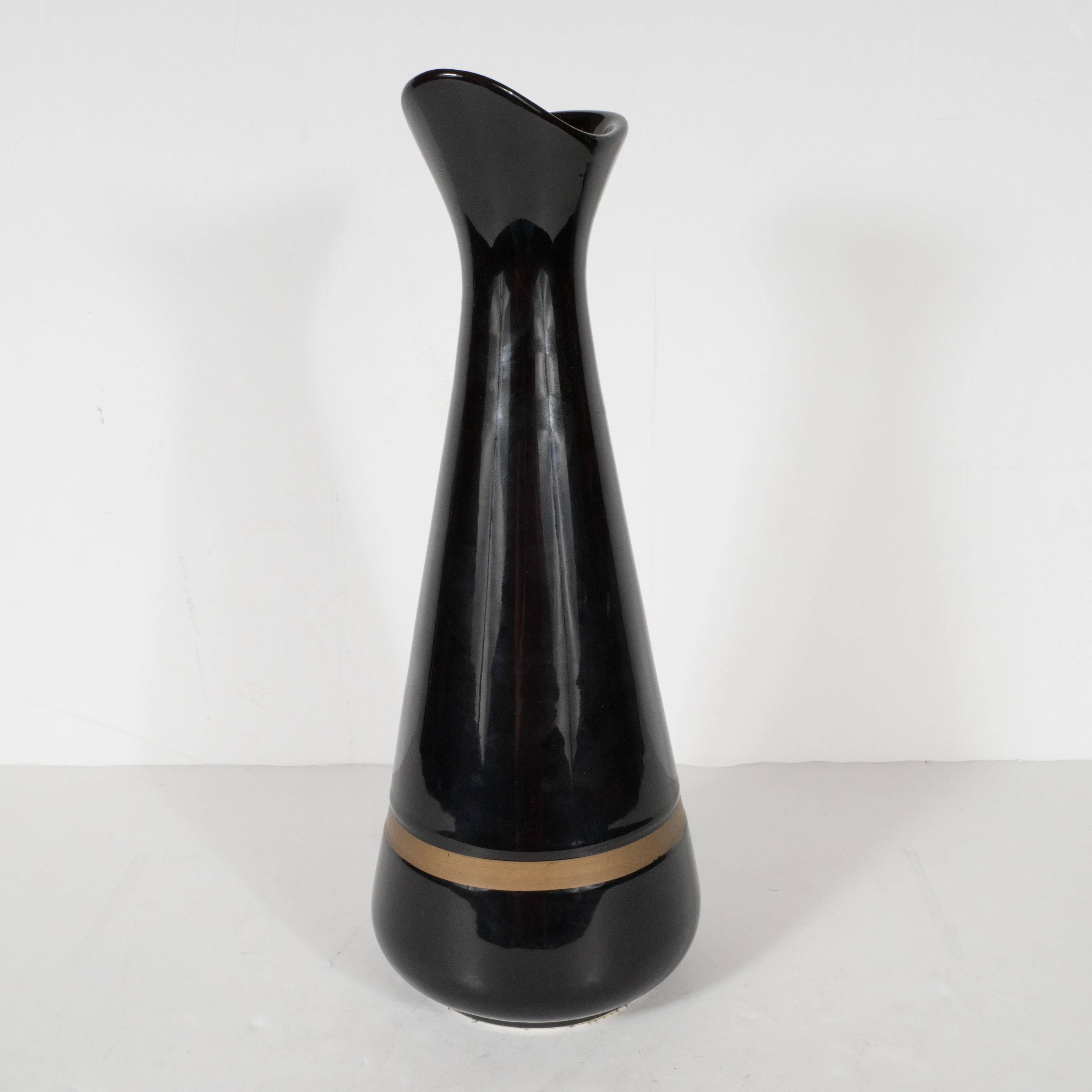 This sophisticated black vase was produced by Hull Pottery- the renowned American producer based in Crooksville, Ohio, circa 1950. The simple hourglass form reads as quintessentially Mid-Century Modernist. The austere palate, consisting of radiant