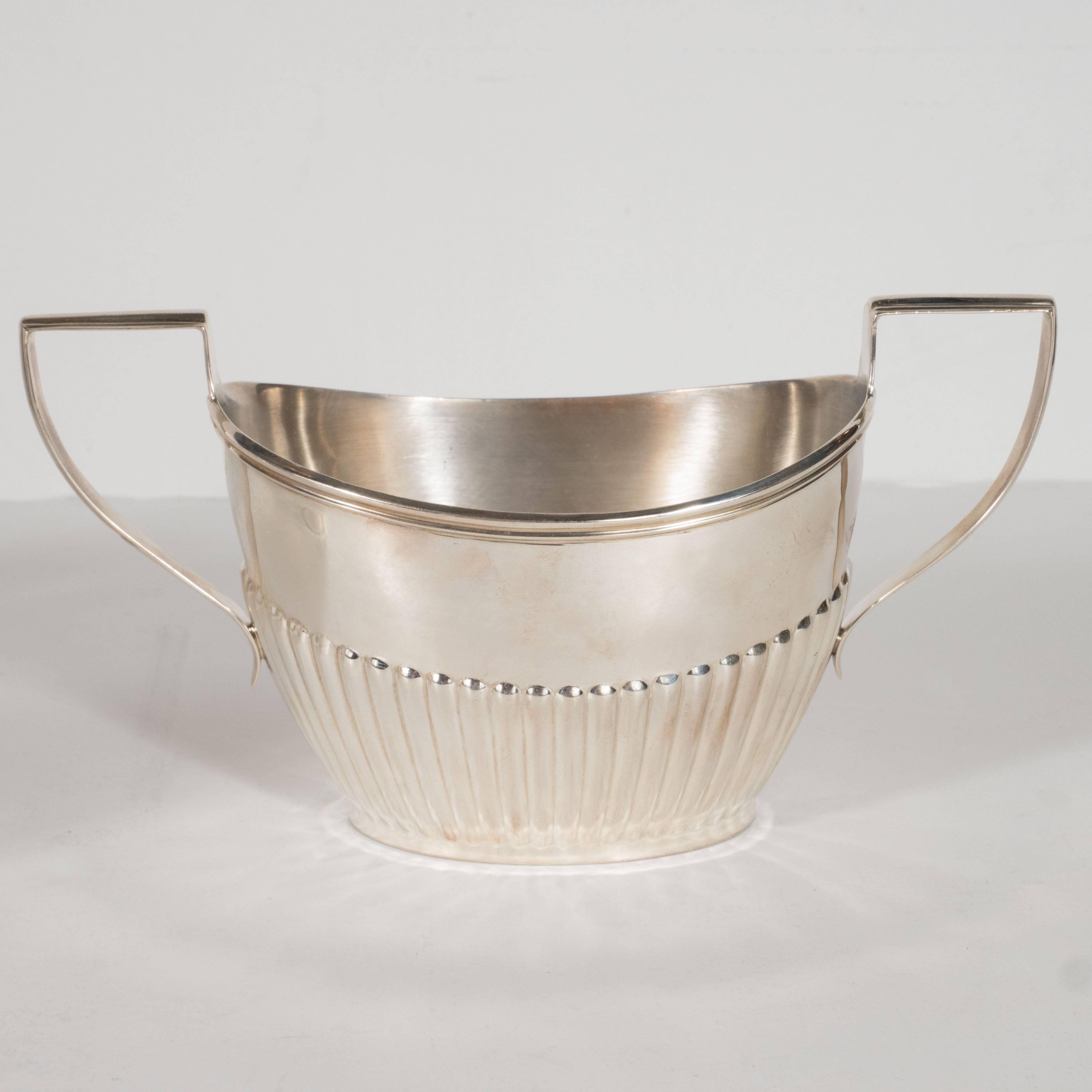 This refined coffee service, which includes a coffee pot, a cream saucer, and a sugar bowl. It was realized by Ryrie- one of the most illustrious silversmiths in Toronto since 1879- in the early 1930s. Each piece features raised fluted tubular