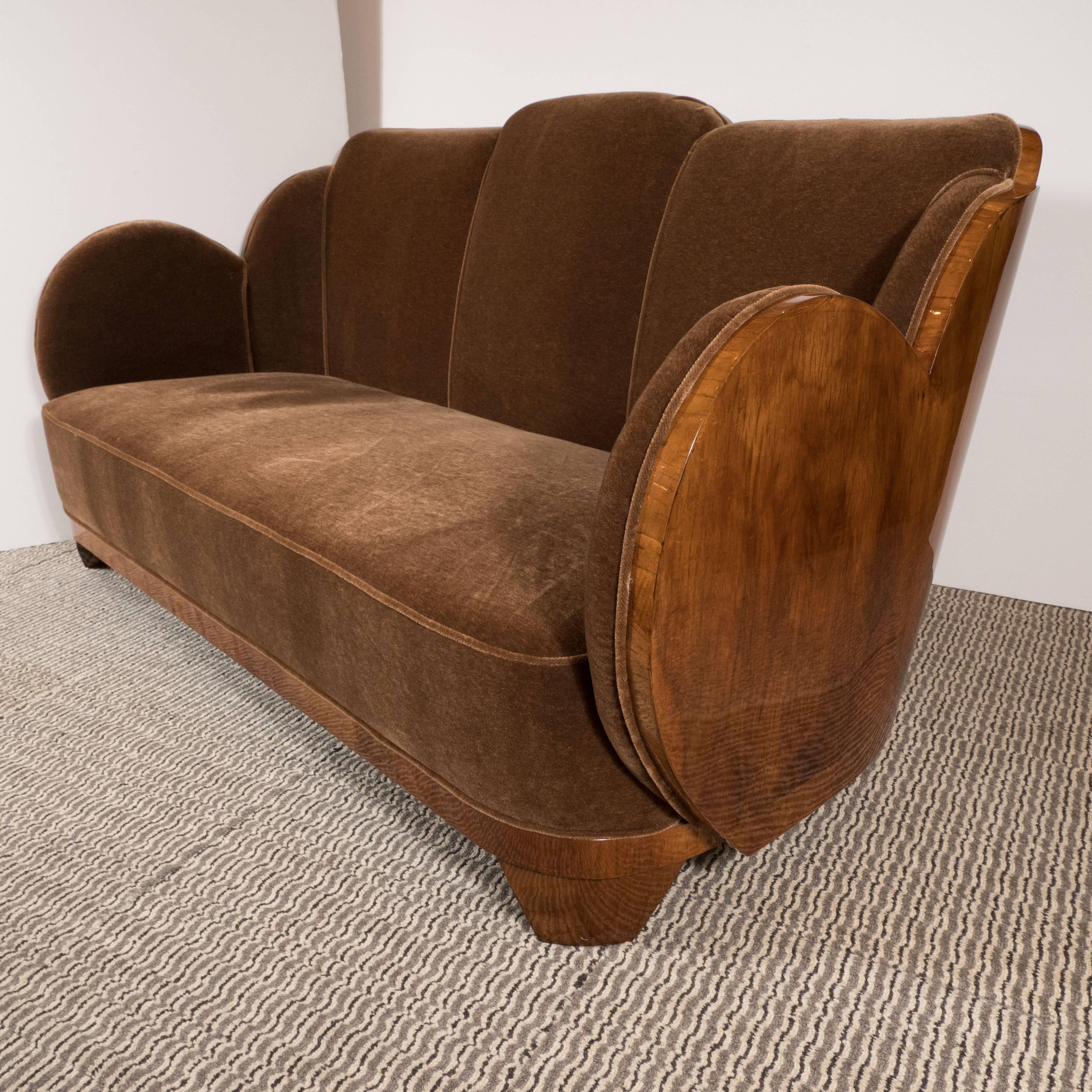 This streamline "Cloud" series Art Deco sofa or loveseat features elegant undulating curves of book-matched walnut, tapered pentagonal feet, perimeter piping, and luxurious mohair in a smoked topaz hue. This impeccably crafted sofa defines