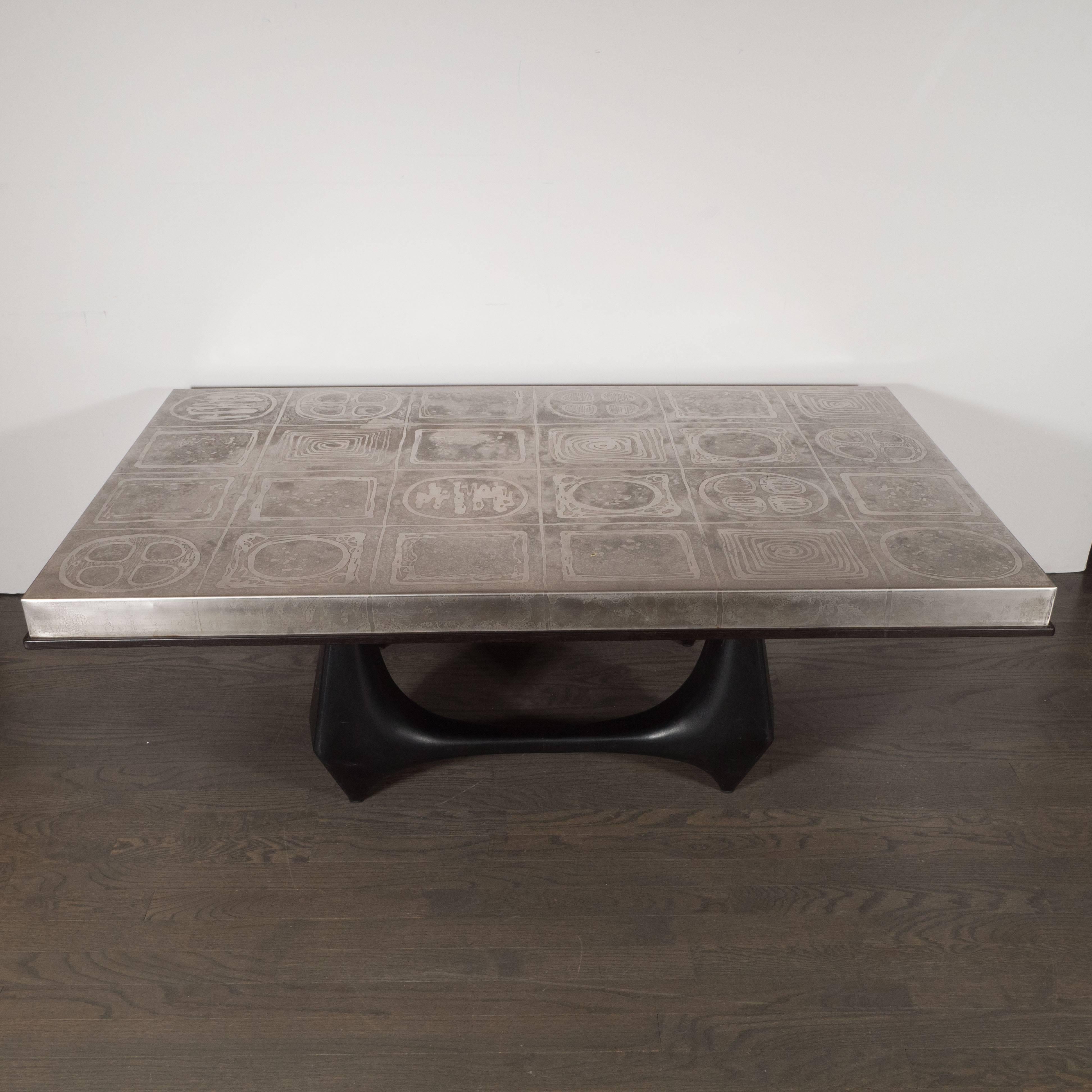 This exceptional Mid-Century modernist table features an array of organic forms acid etched into its aluminum top and circumscribed with an ebonized walnut border. The sculptural base has been forged from aluminum and coated in black enamel. This