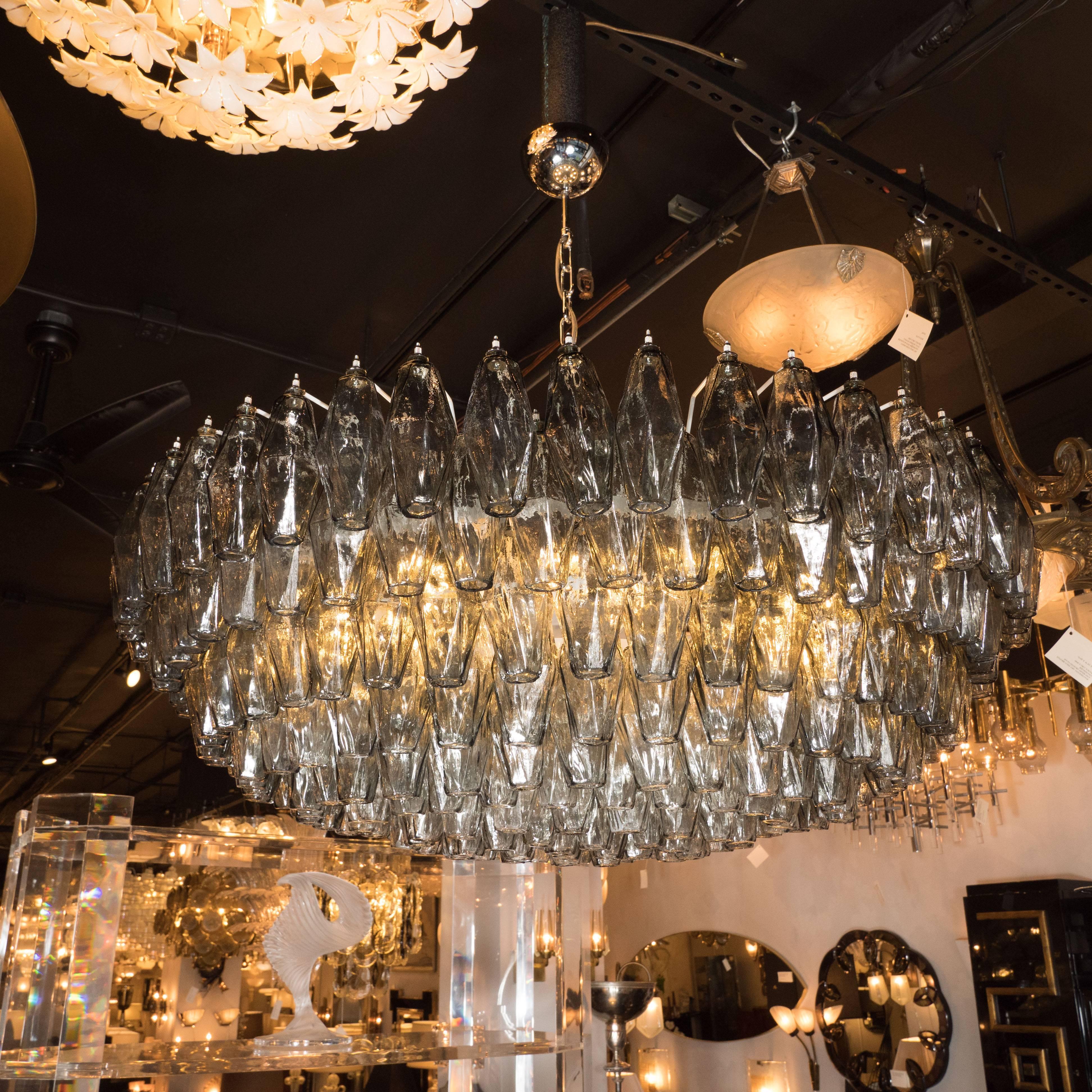 This impressive Murano glass chandelier, in the manner of Venini, features a constellation of handblown Murano glass polyhedral glass shades in a smoked pewter grey hue. Each shade has been hand blown and individually hung from its frame.
