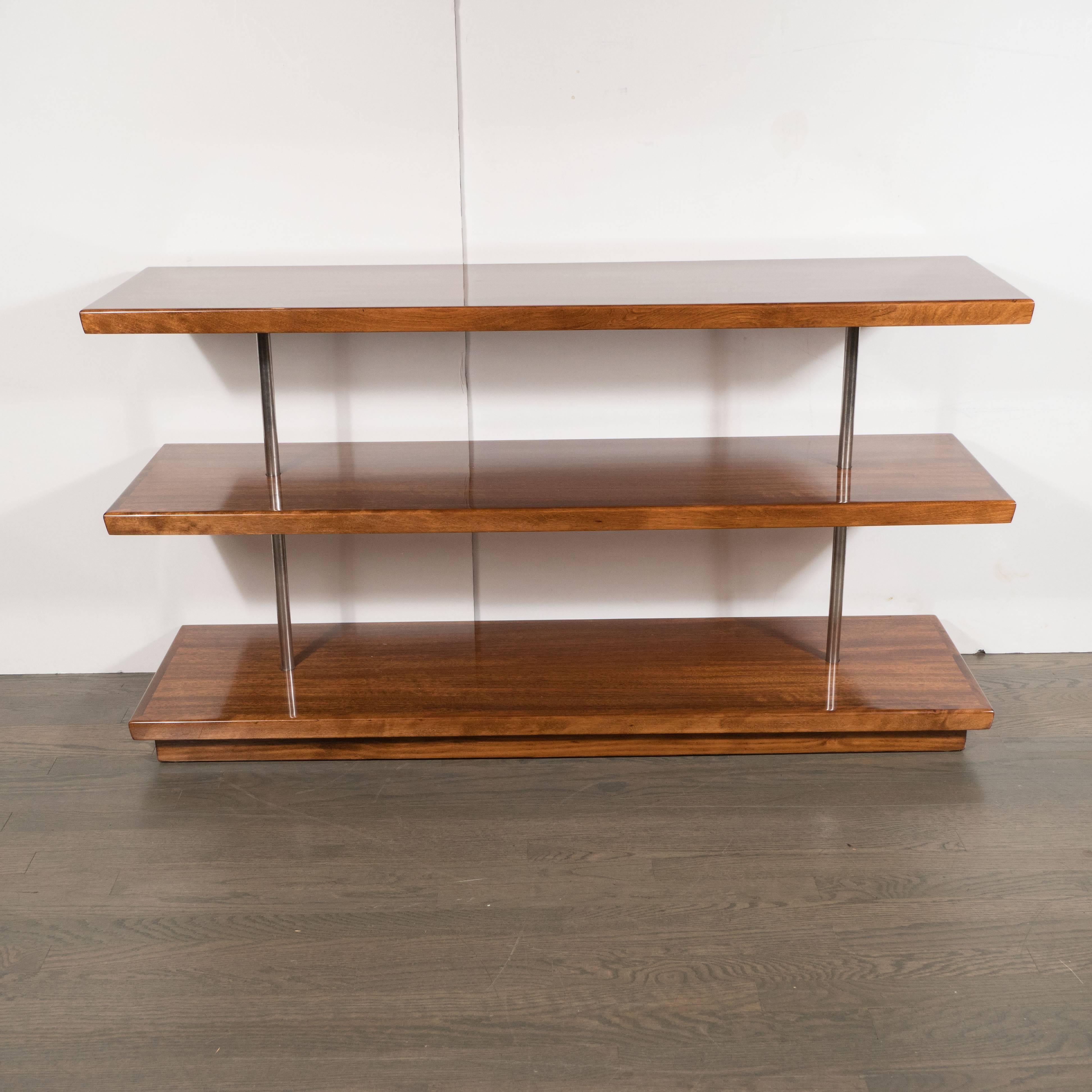 This elegant Art Deco skyscraper style piece by Gilbert Rohde features book-matched Acacia shelves circumscribed by walnut on the perimeter with brushed aluminium rods supporting the structure. It represents an important (not to mention stunning)