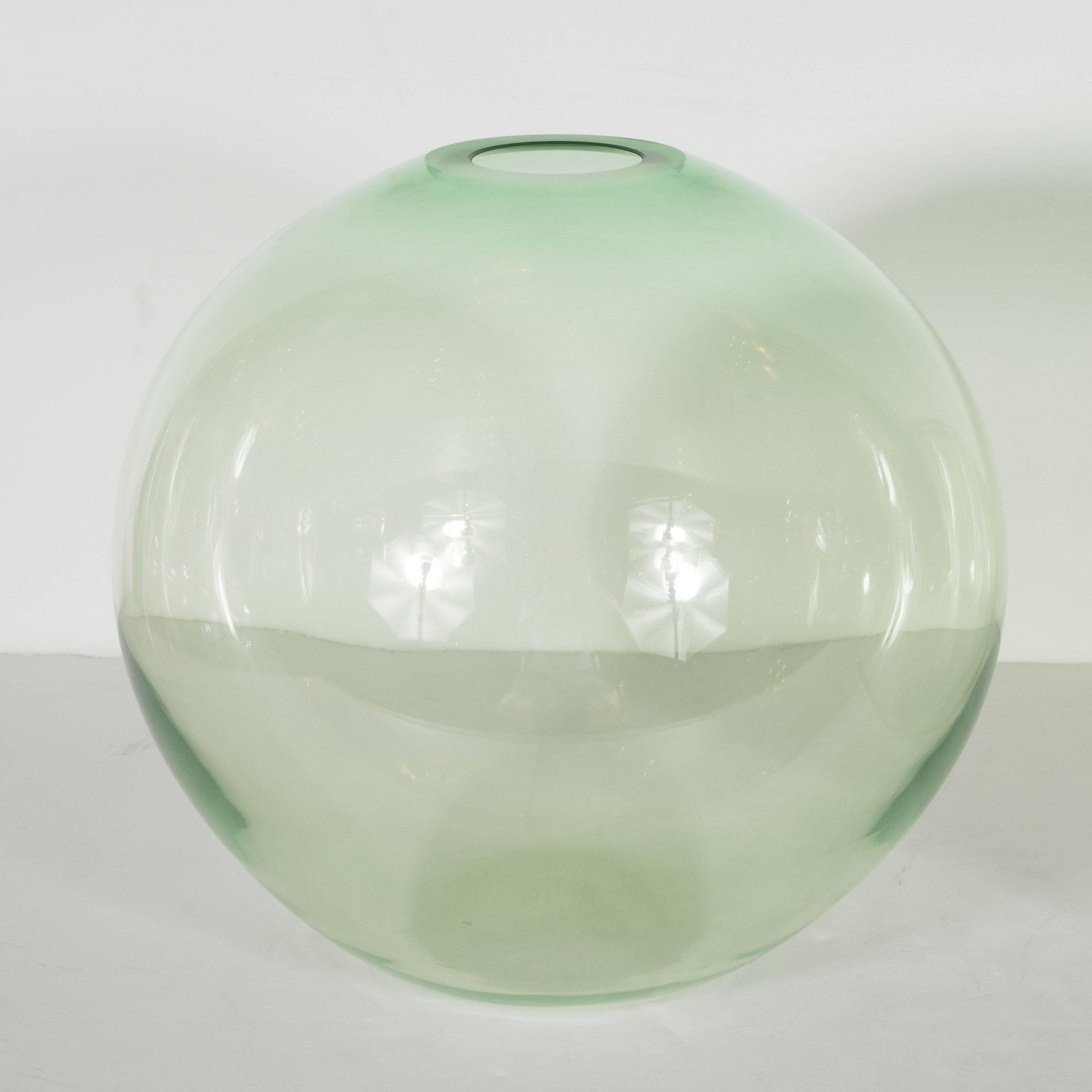 This pair of globular vases have been handblown by the esteemed Brooklyn based artist Nick Leonoff in an emerald hue of translucent glass. With their radiant palate and organic forms, they are perfect as functional vases for presenting flowers, and