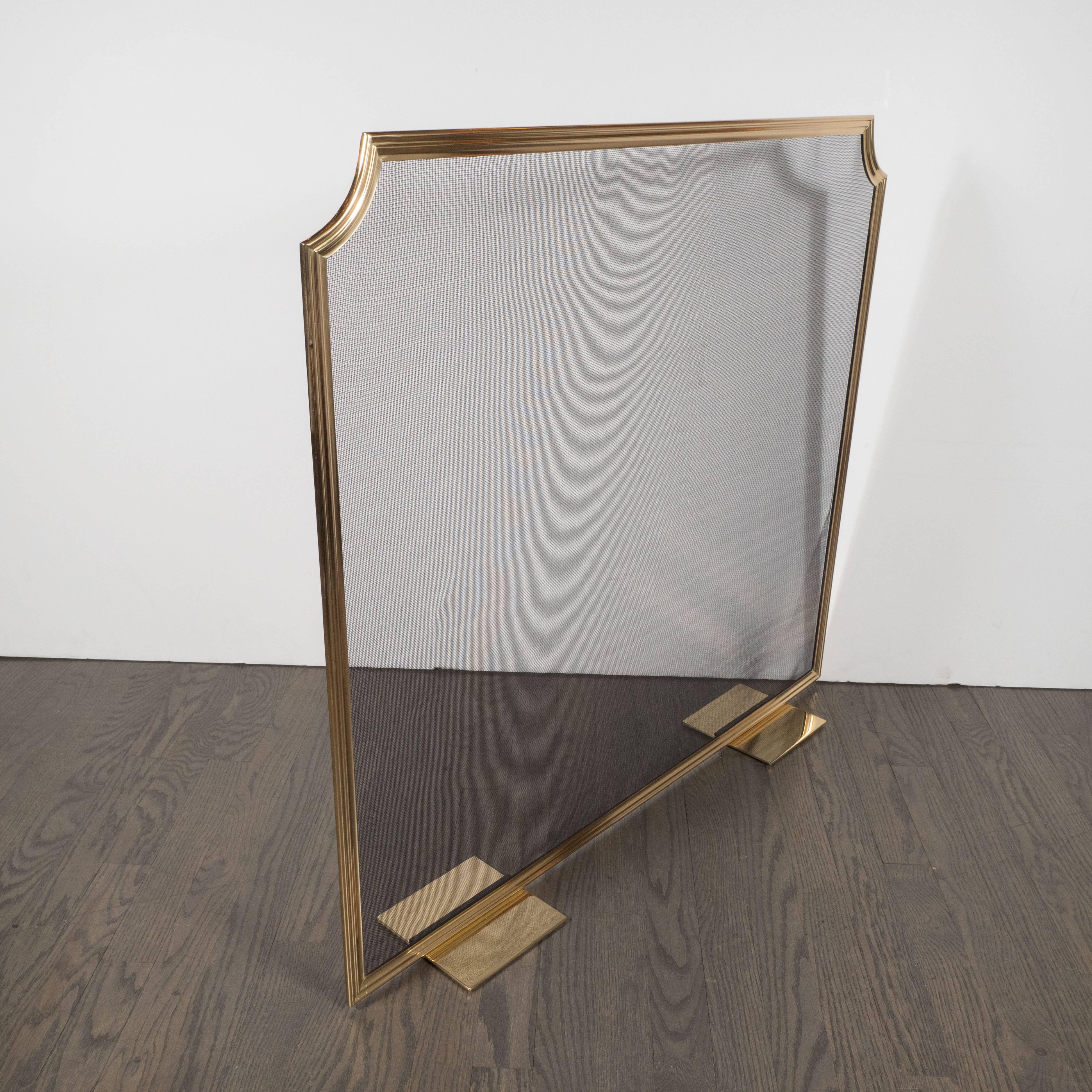This elegant firescreen was custom realized by artisans in New York state, exclusively for us. It features a reeded brass perimeter with scalloped corners, fine square steel mesh, and flat square brass feet. With its austere form and luxe materials,