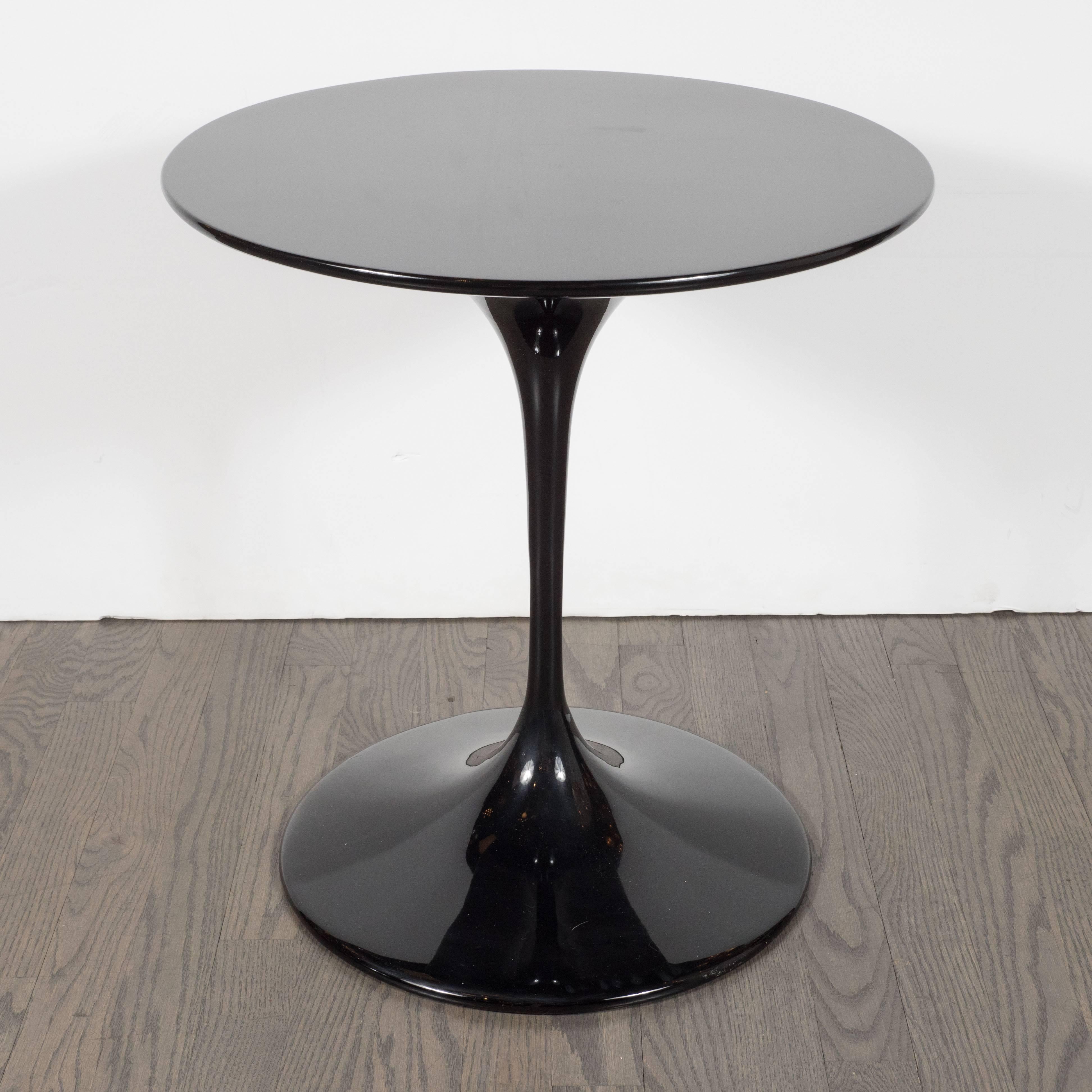 This sophisticated table in the manner of Eero Saarinen in lustrous black features a lacquer top and a cast iron base, also coated in lacquer, in a matching tone. With its organic lines and radiant finish, this piece represents one of the most