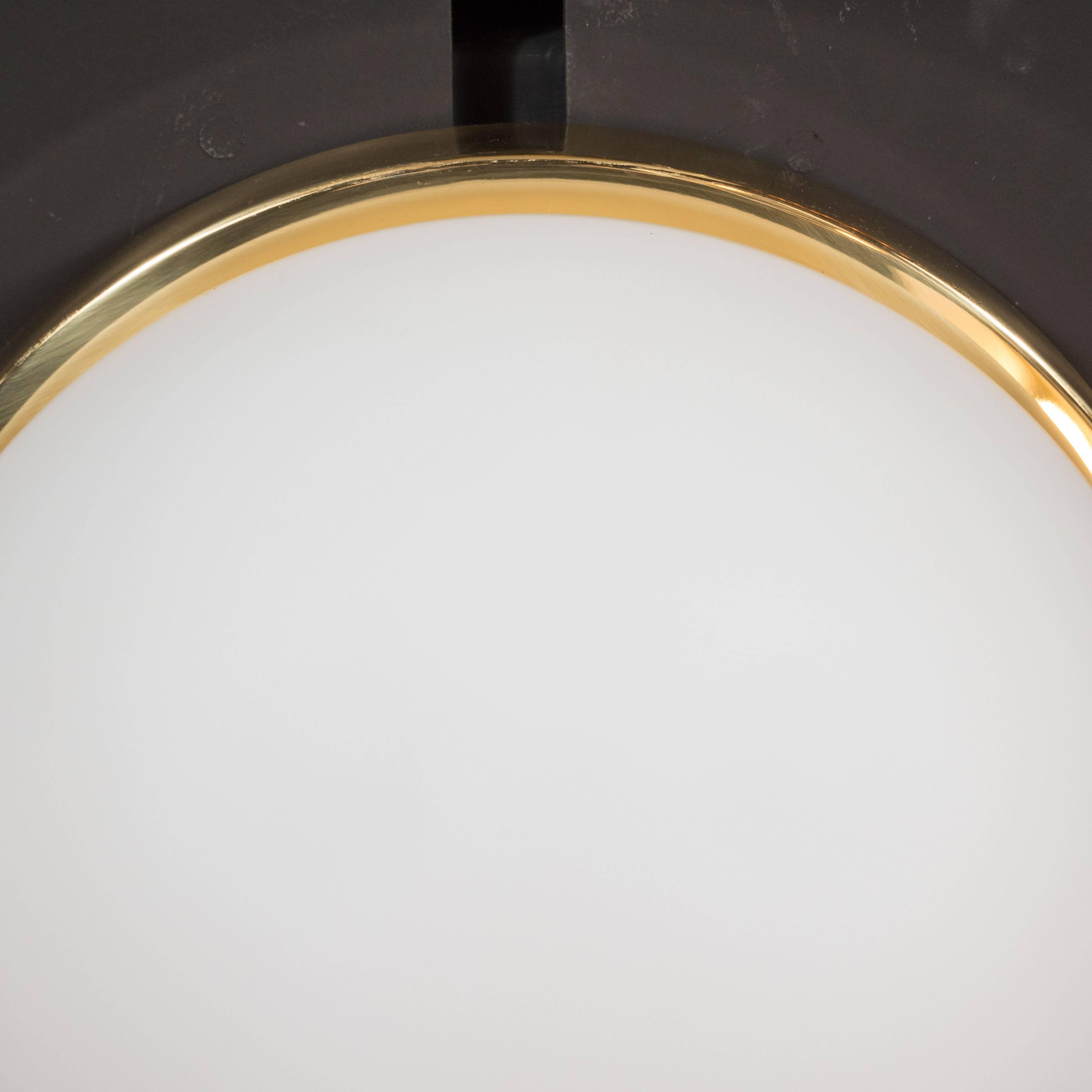 This frosted glass fixture was produced by the esteemed Glashütte Limburg in Germany, circa 1960. It is composed of a domed shape frosted glass with a circular skyscraper style brass base. These fixtures are chic, elegant and timeless, blending