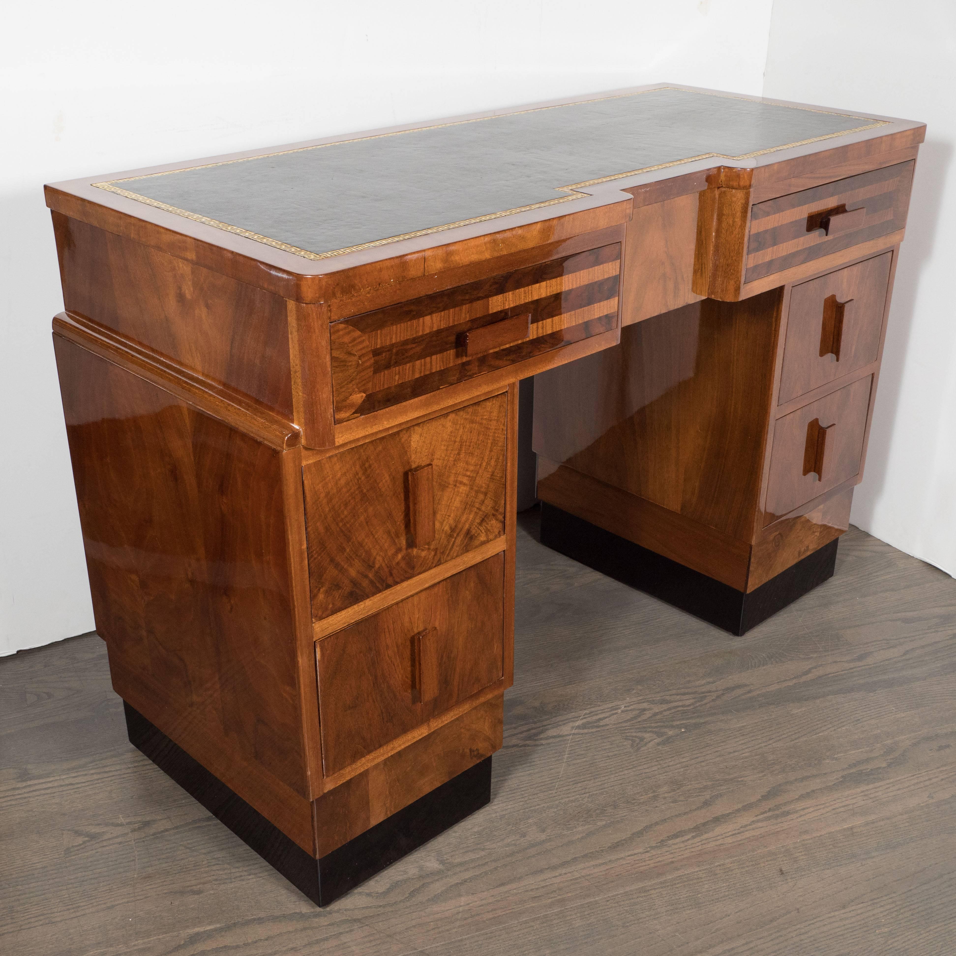 This stunning Art Deco skyscraper style desk features a black leather top with a Greek Key design inscribed in 24-karat gilt around the perimeter. There are two bookmatched walnut drawers at top with horizontal rectangular pulls and parallel