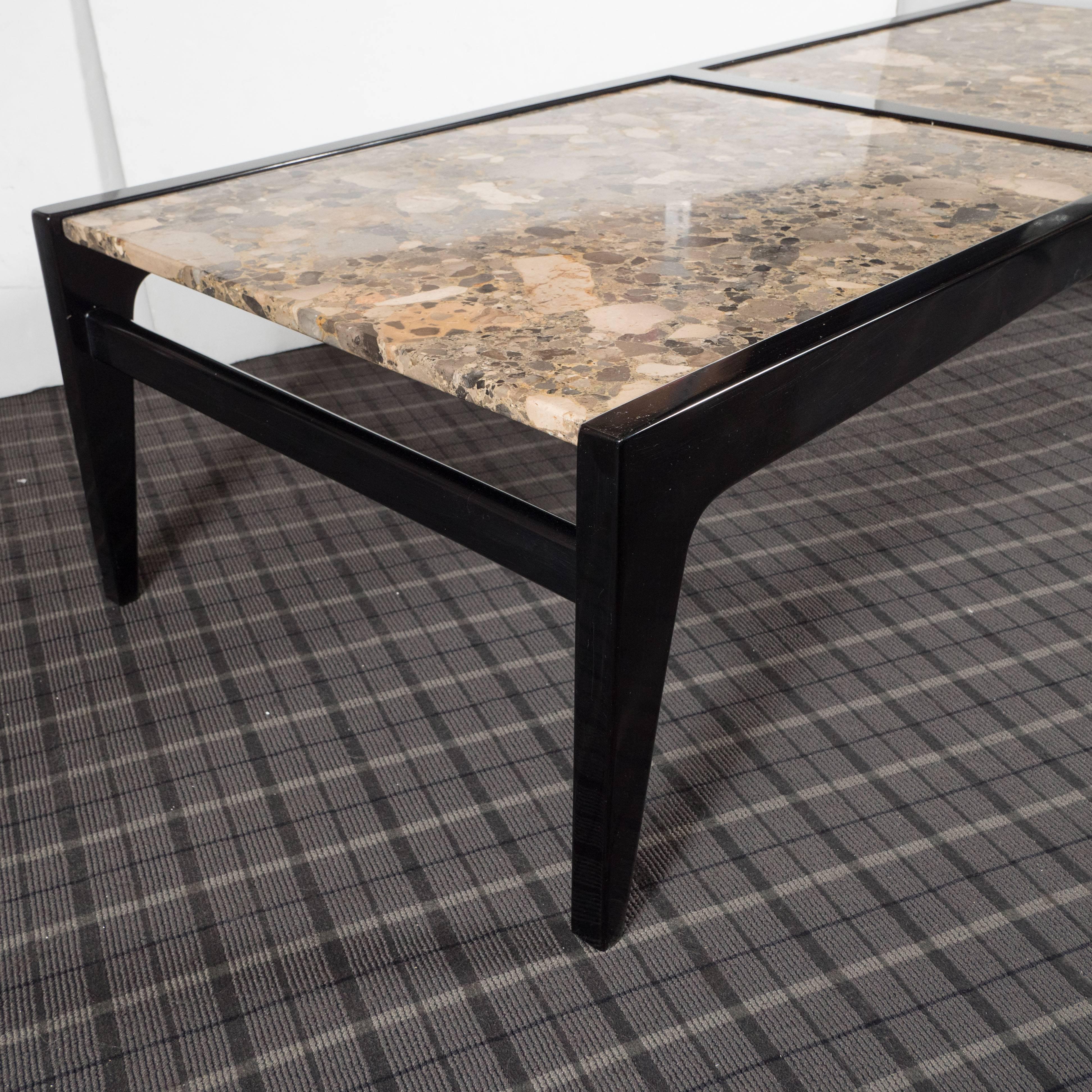 This sophisticated Mid-Century Modernist table features a stunning tabletop composed of two slabs of polished metamorphic granite each containing a wealth of pebbles, granules, and cobbles. Within the rock grain, there is a galaxy of forms in earth