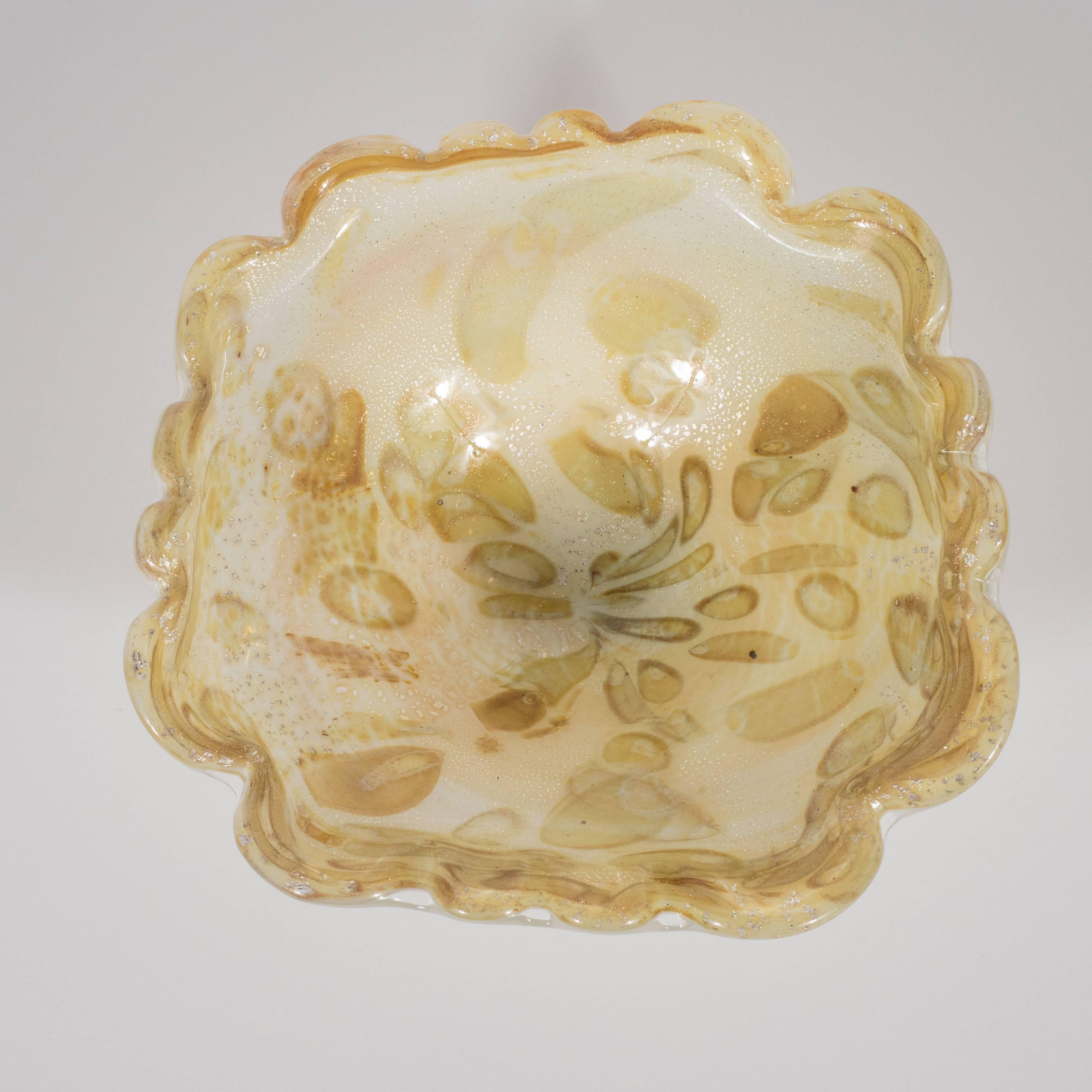This stunning handblown Murano glass bowl features scalloped edges and a wealth of specter-like forms in shades of champagne, oyster shell and pistachio emanating from the center as well as an abundance of white gold flecks throughout. With its