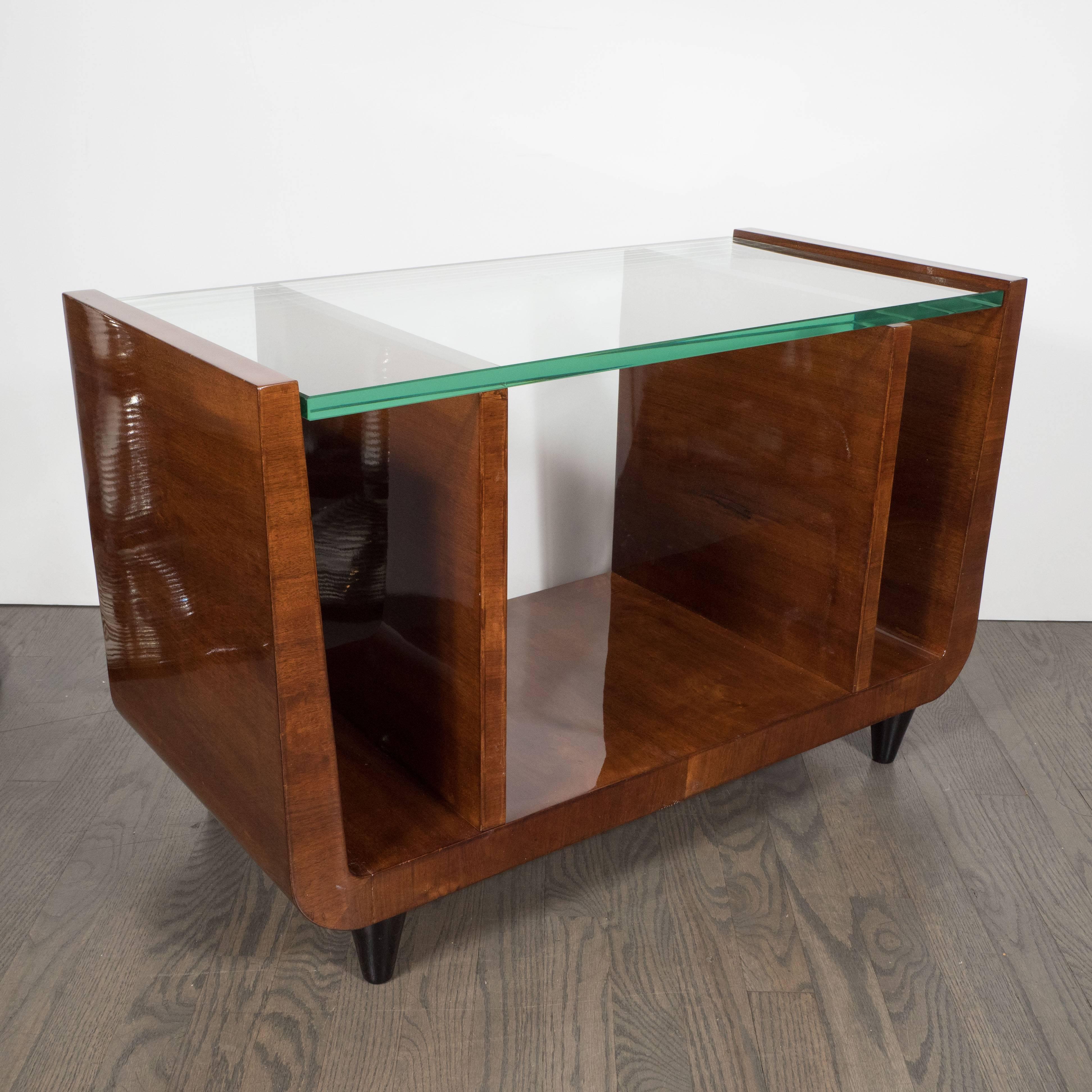 This elegant streamline bookmatched walnut, black lacquer and glass cocktail/ occasional table was realized in France, circa 1935. With its timelessly elegant design- featuring four vertical planes extended from the base and simple black lacquer